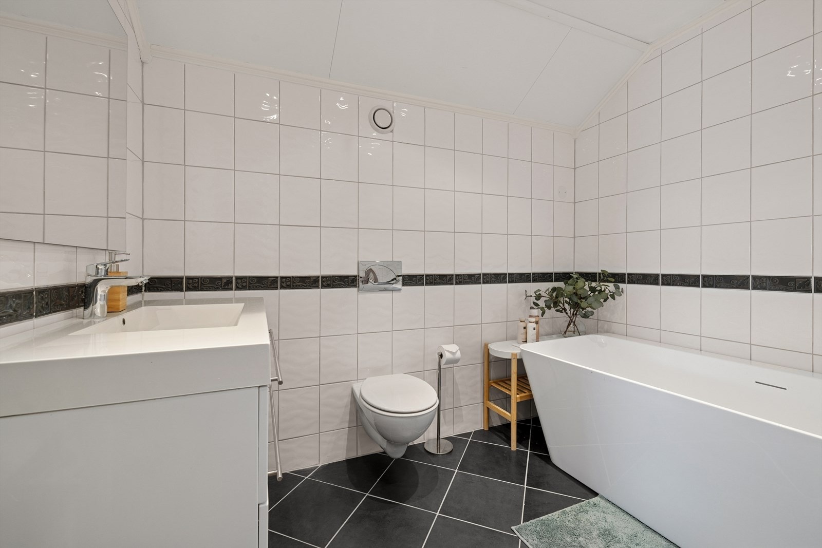 Badet er utstyrt med vegghengt toalett, badekar, samt baderomsinnredning med nedfelt servant. Galleribilde