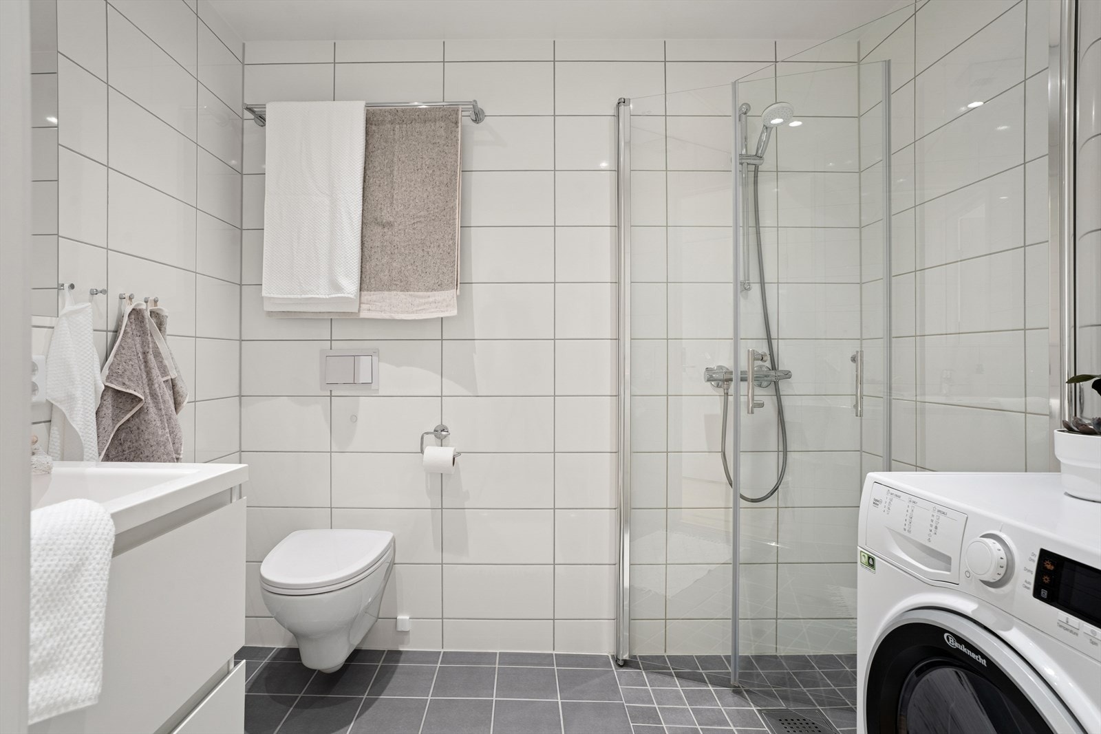 Badet er videre utstyrt med veggmontert toalett, dusjhjørne med innfellbare glassdører og servant med ettgreps blandebatteri. Våtrommet er fra 2020 og har mekanisk avtrekk Galleribilde