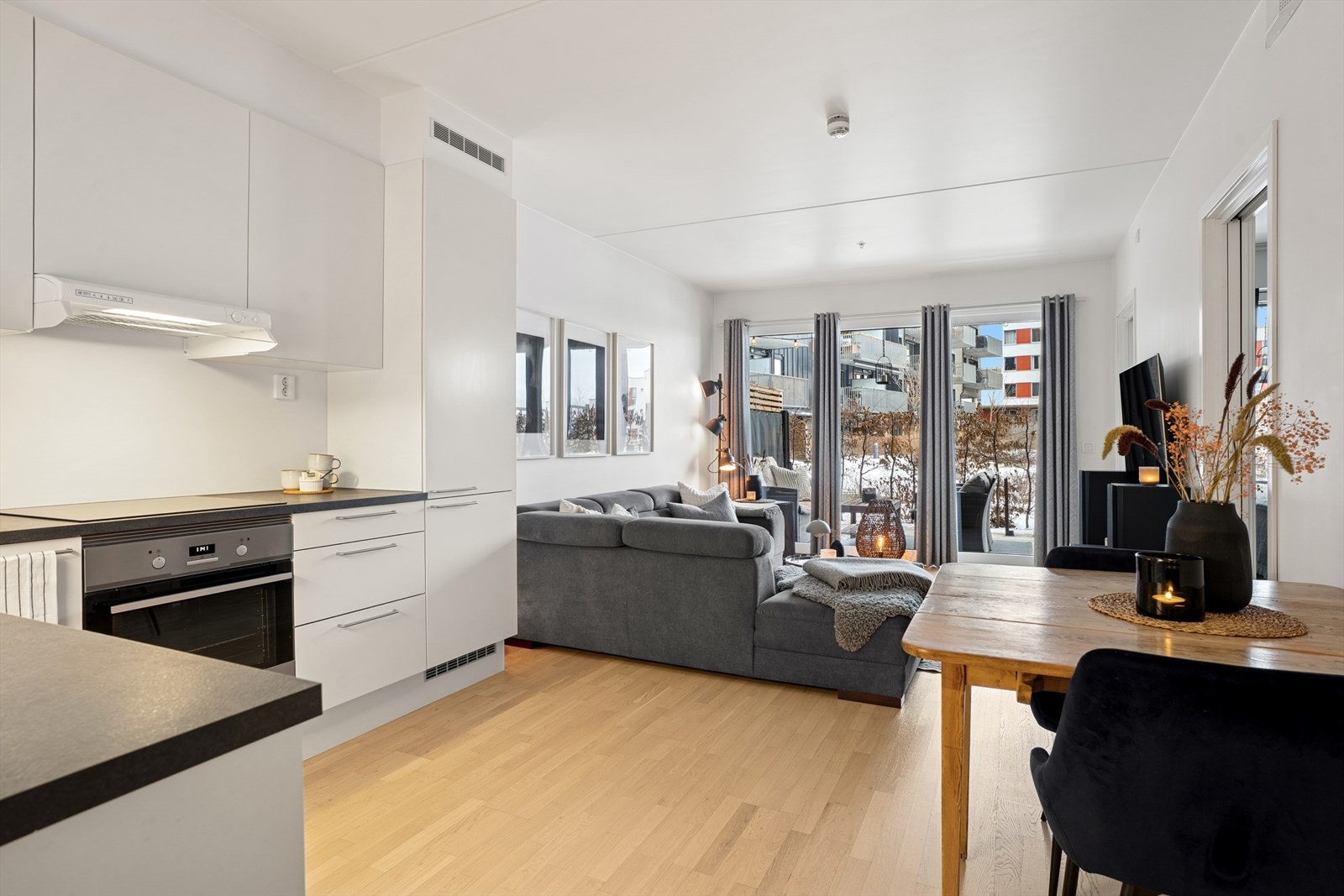 En balkongdør fører ut til en sydvendt markterrasse med tregulv, som fungerer som en fin forlengelse av rommet på varme sommerdager Galleribilde