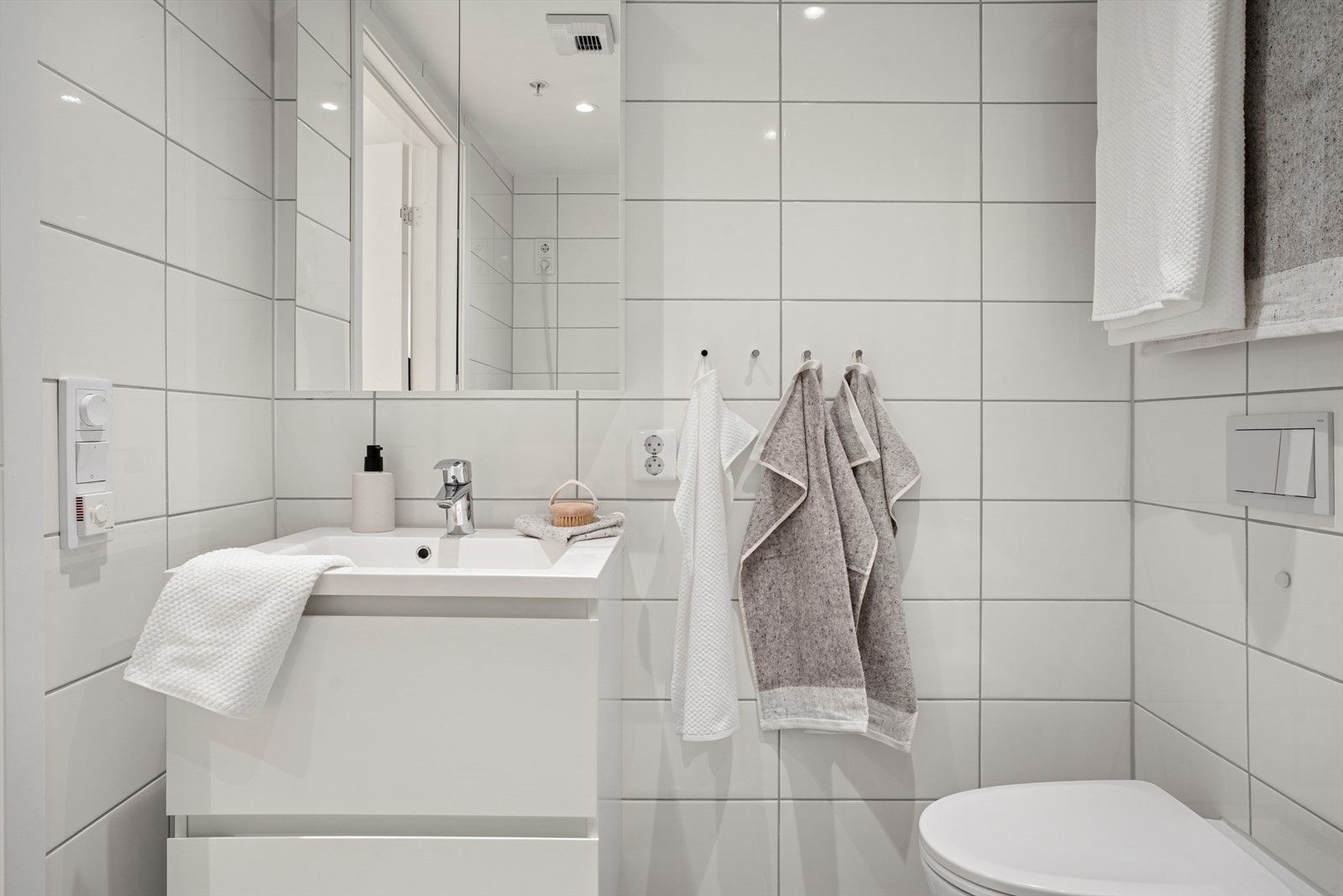 Innredningen består av moderne, glatte fronter, speil over servanten og en praktisk skuffeseksjon som gir rikelig med oppbevaringsplass Galleribilde