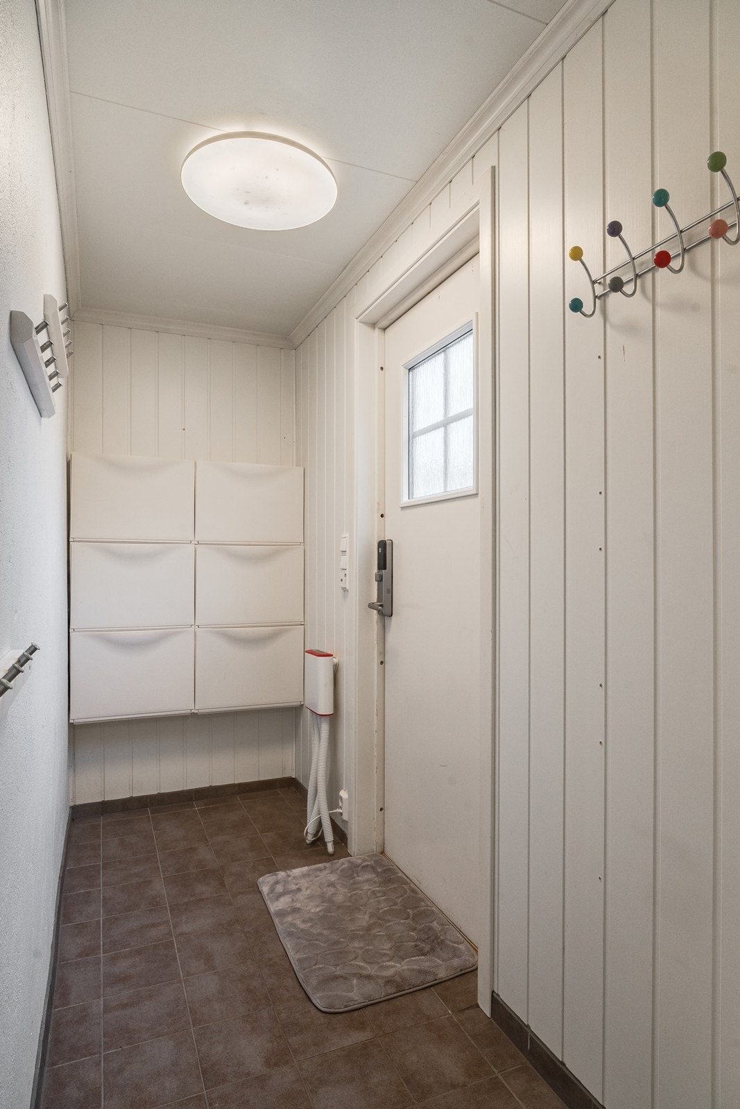 Vaskerommet har tilhørende vindfang med bi-inngang som også har flislagt gulv og oppheng for yttertøy. (rommet er ikke godkjent ref. pkt. ferdigattest). Galleribilde