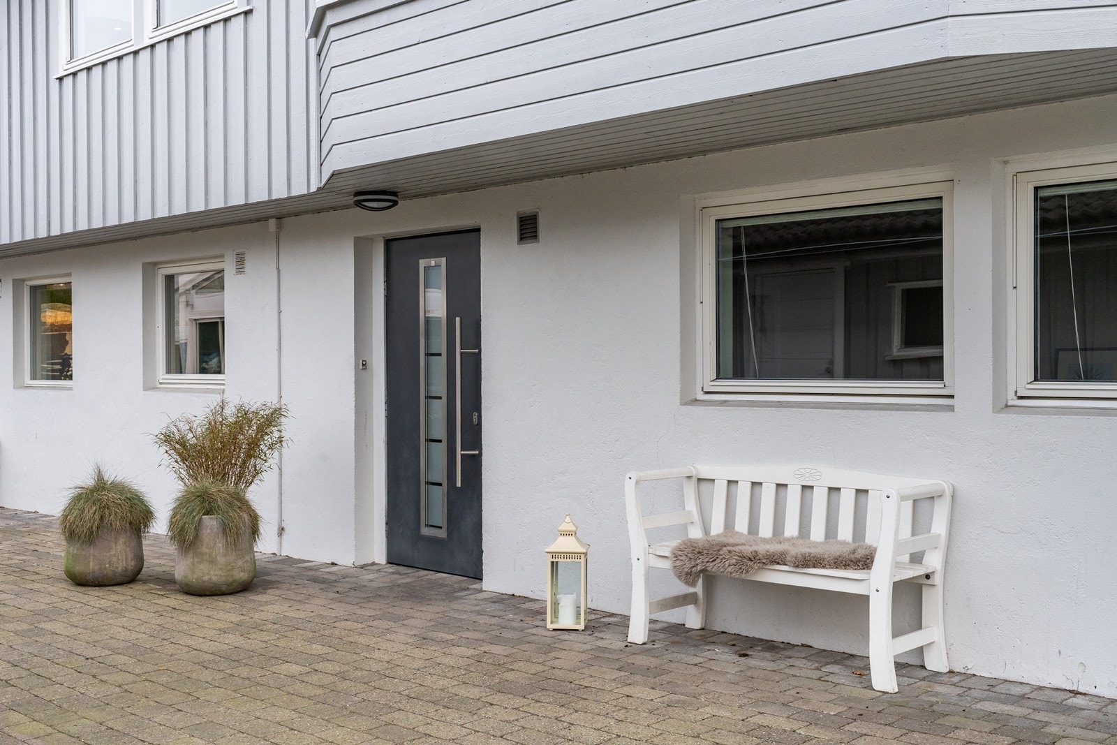 Innbydende inngangsparti med stilig ytterdør og belegningsstein. Galleribilde