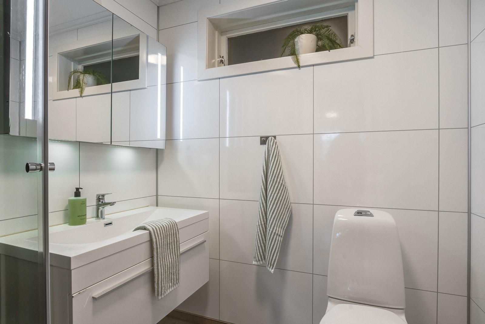 Lyst og moderne bad med baderomsplater på vegg og fliser med varmekabler i gulv. Galleribilde