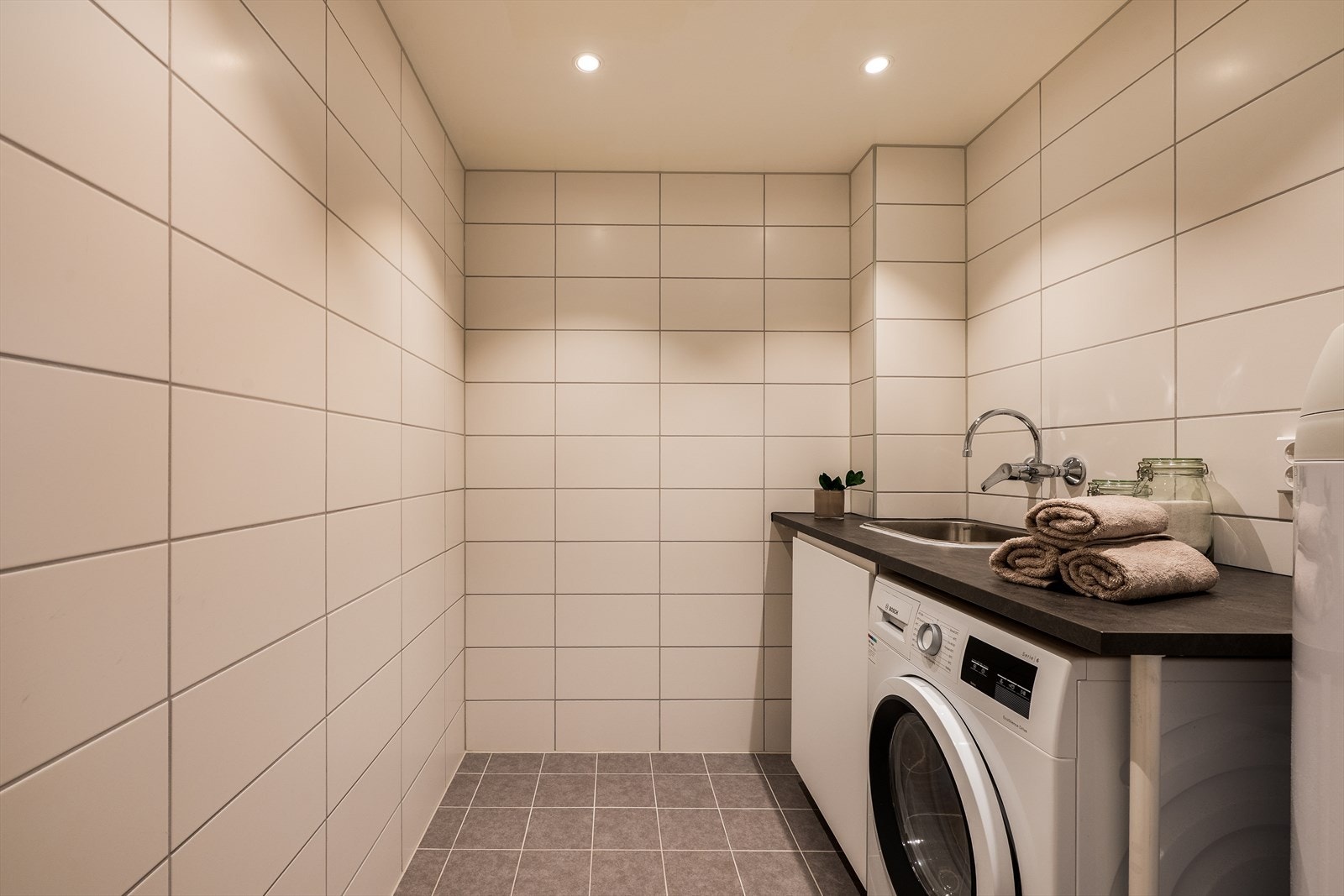 Praktisk vaskerom med gulv- og veggfliser, pusset opp i regi av borettslaget i 2021-2022. Rommet har opplegg for vaskemaskin. Galleribilde