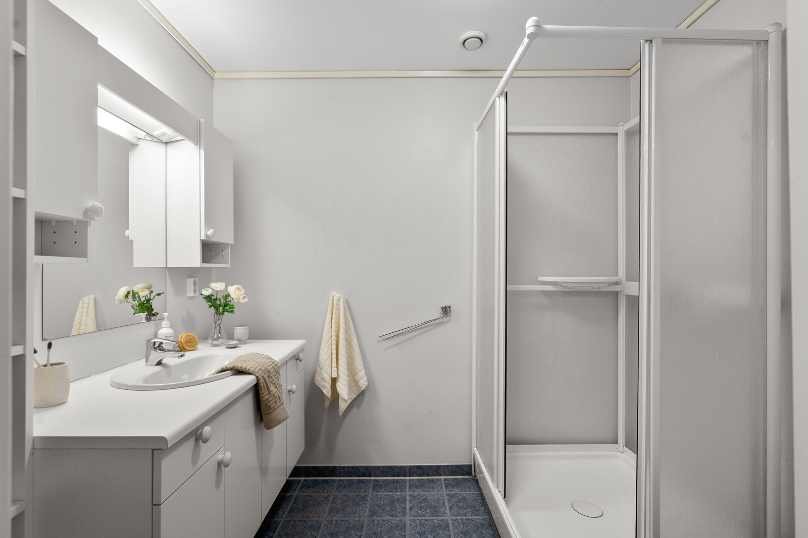 Bad har fliser på gulv og våtromstapet på vegger. Innredet med vask i seksjon, toalett og dusjkabinett. Galleribilde