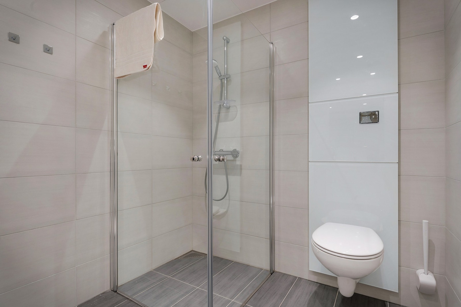 Badet er helfliset med veggehengt toalett og dusjhjørne med foldedører for mer plassutnytelse. Galleribilde