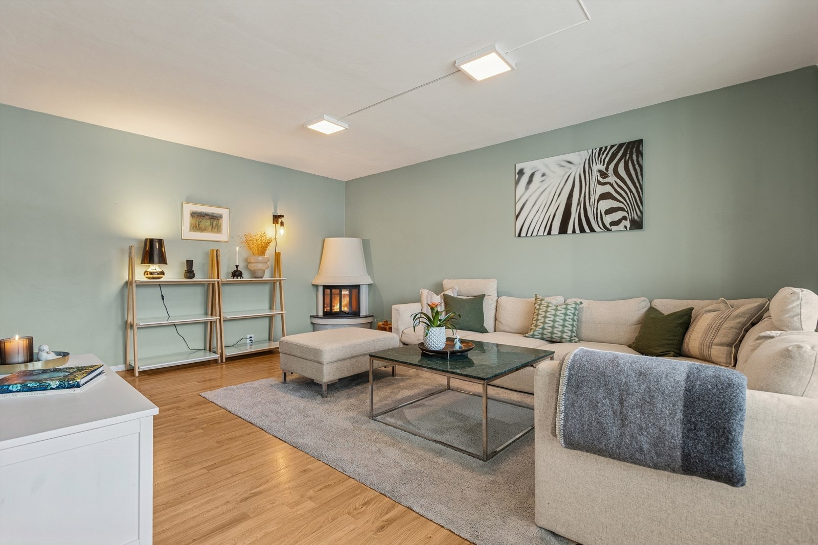 Romslig stue med stor TV-vegg, åpen planløsning og store vindusflater som slipper inn rikelig naturlig lys. Galleribilde