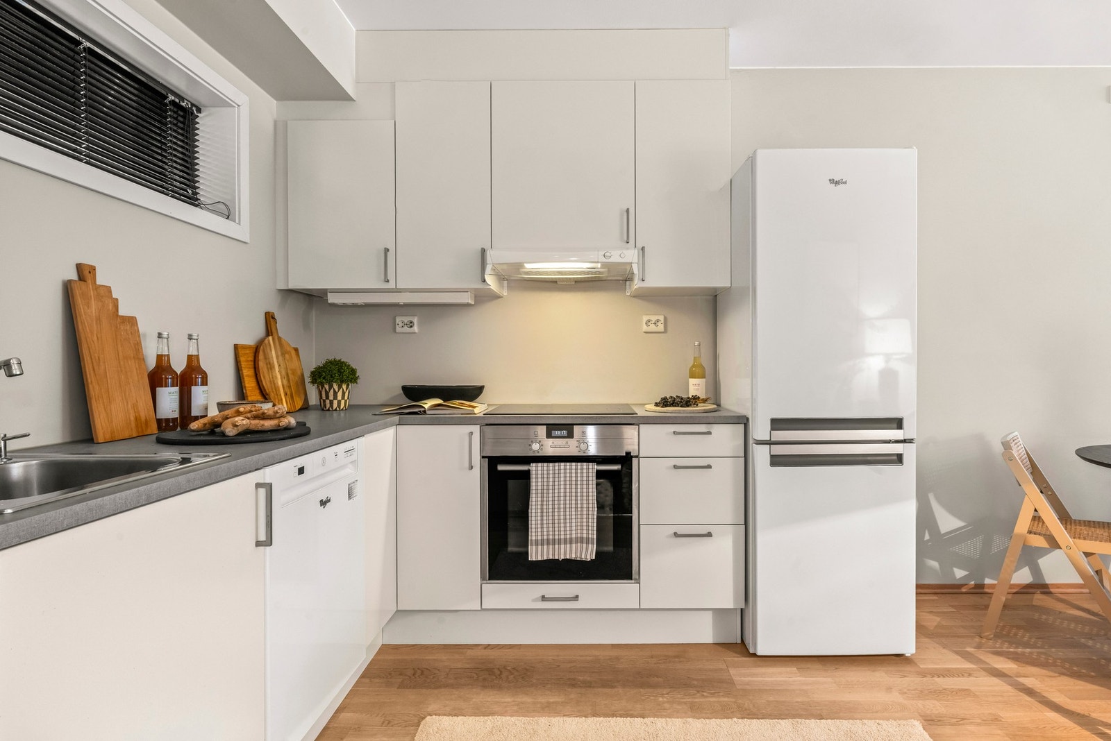 Lys kjøkkeninnredning med over- og underskap med slette fronter og laminat benkeplate Galleribilde