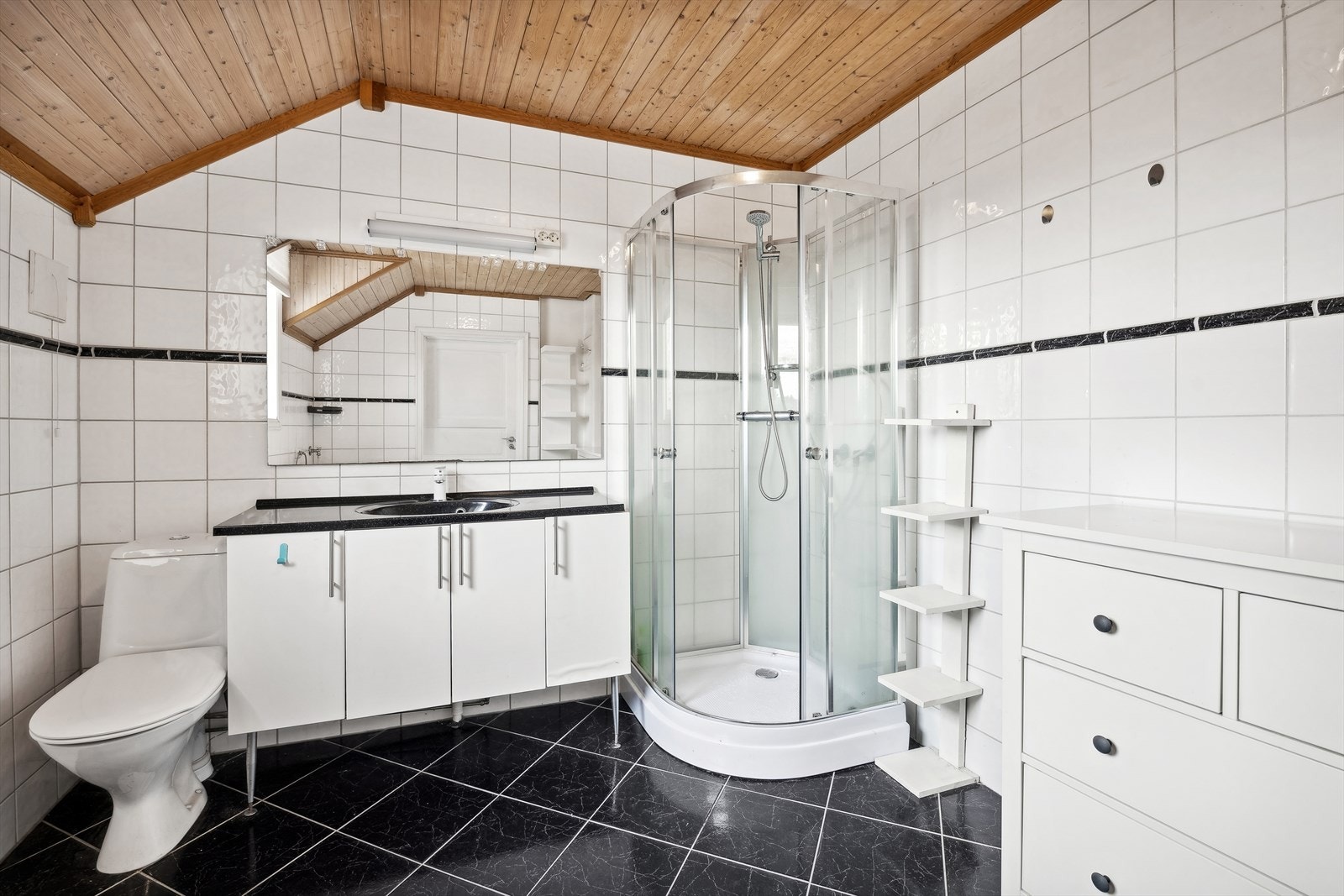 Badet er beliggende i andre etasje, og er innredet med baderomsinnredning med servant, speil, toalett og dusjkabinett. Galleribilde