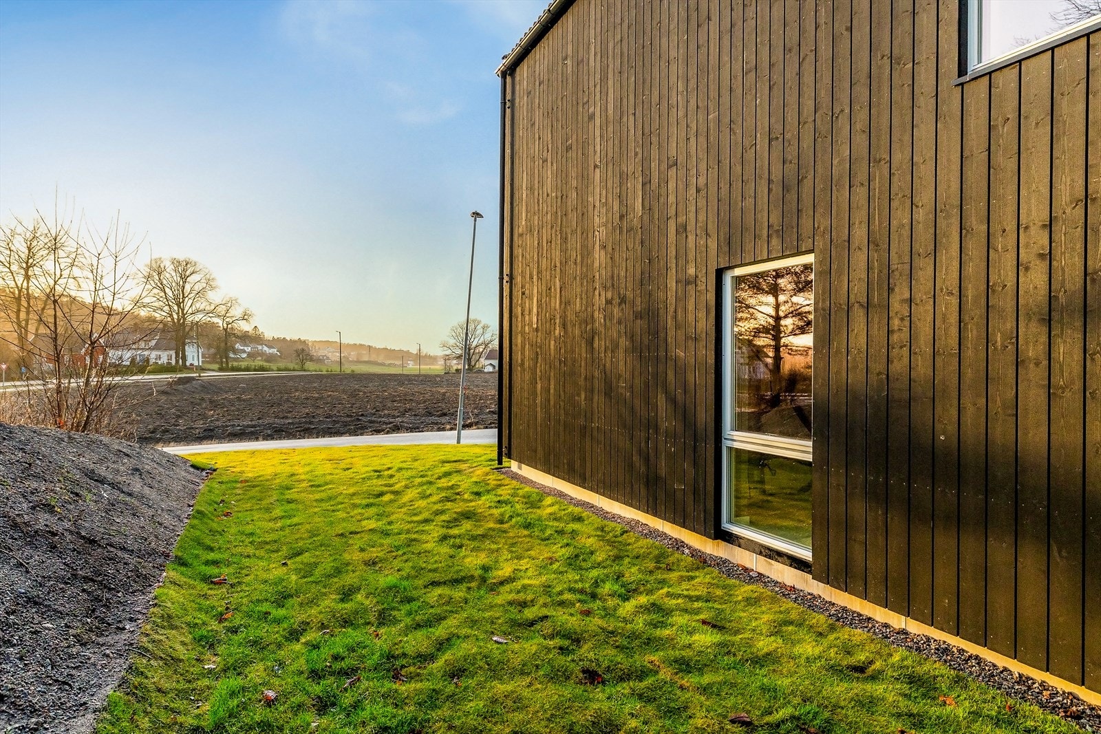 Lettstelt tomt med plen og asfaltert gårdsplass. Galleribilde