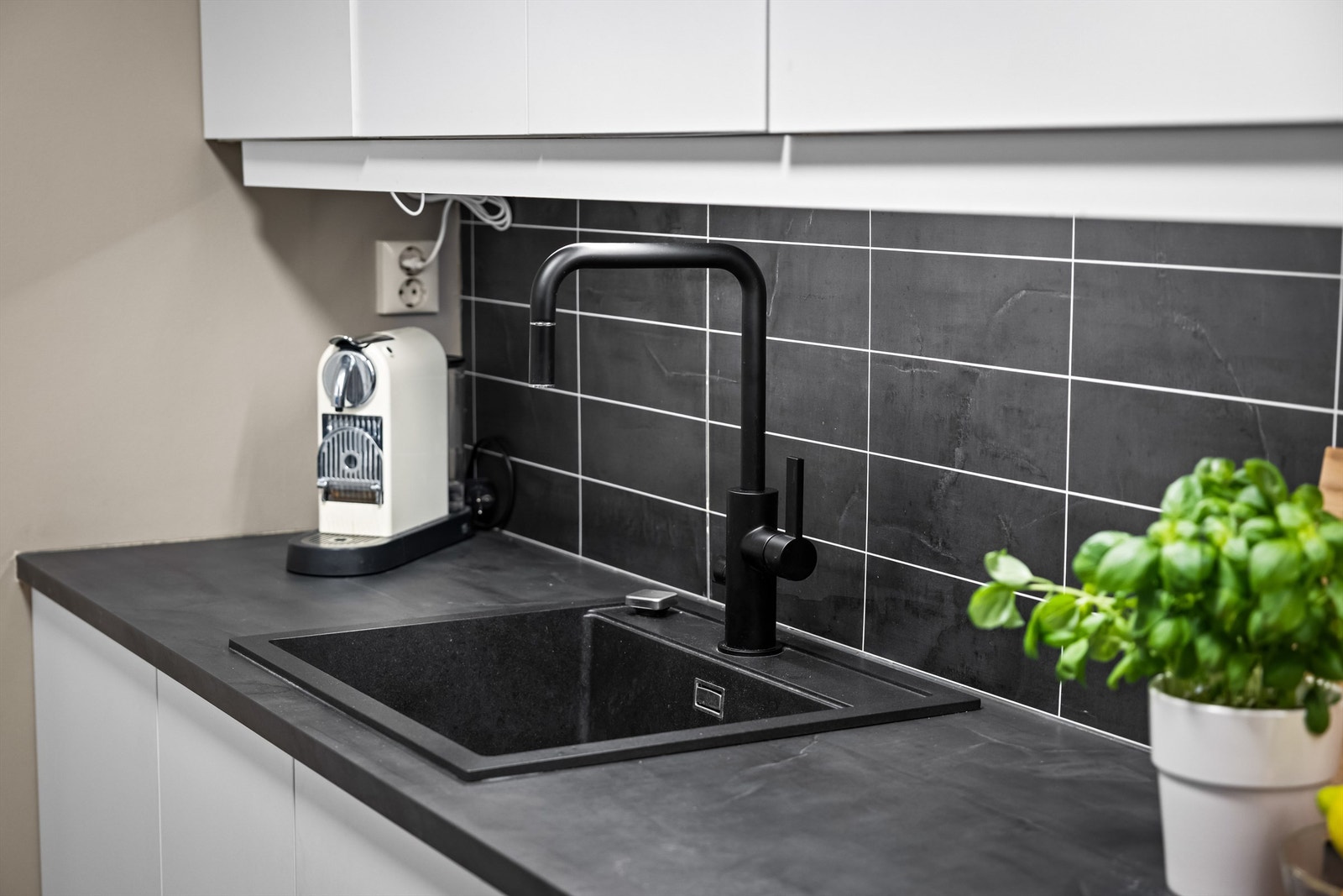 Moderne, sort blandebatteri og en underlimt oppvaskkum i mørkt komposittmateriale. Galleribilde