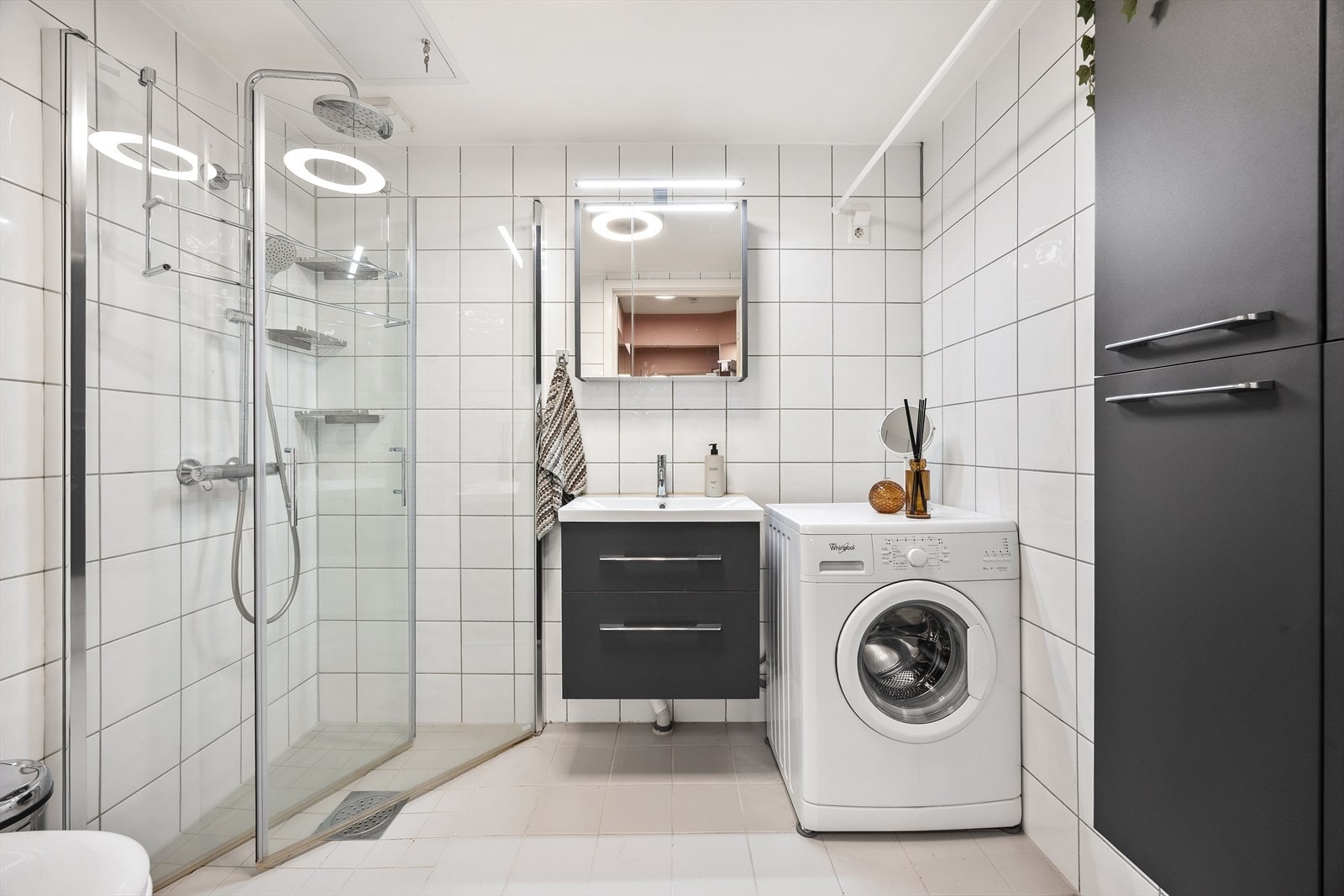 Helflist bad med servantinnredning, vegghengt skap og opplegg for vaskemaskin. Galleribilde