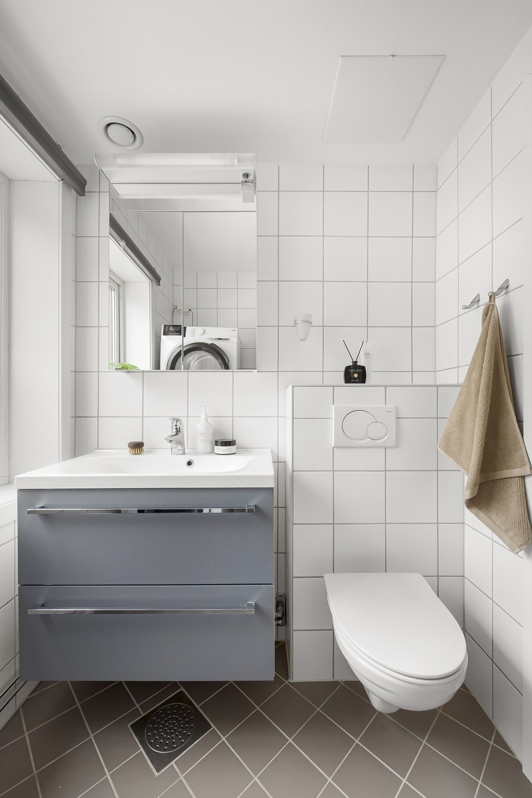 Badet er innredet med veggmontert innredning med heldekkende servant. Over servant er det speilskap med belysning og stikkontakt. Dusjnisjen er skjermet med buede glassdører. Videre er det vegghengt toalett og opplegg for vaskemaskin. Galleribilde