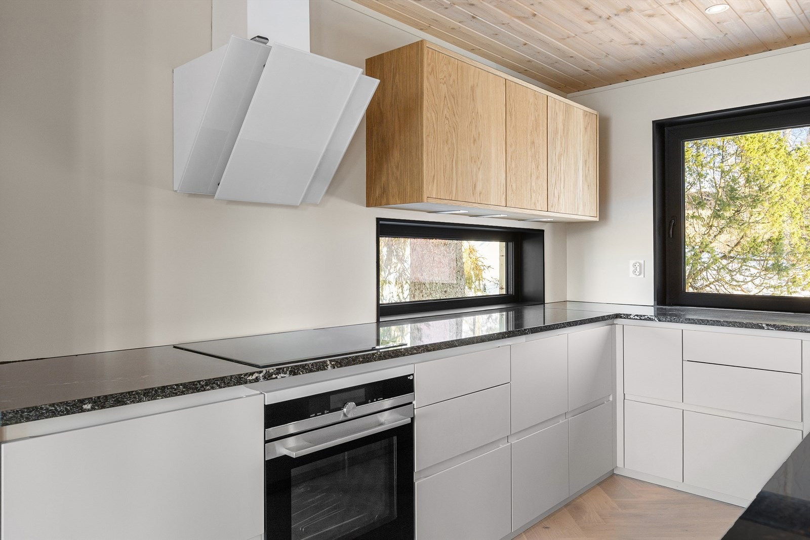 Det er integrerte hvitevarer og benkeplate i stein. Vindusflatene sikrer gode lysforhold for kokken. Galleribilde