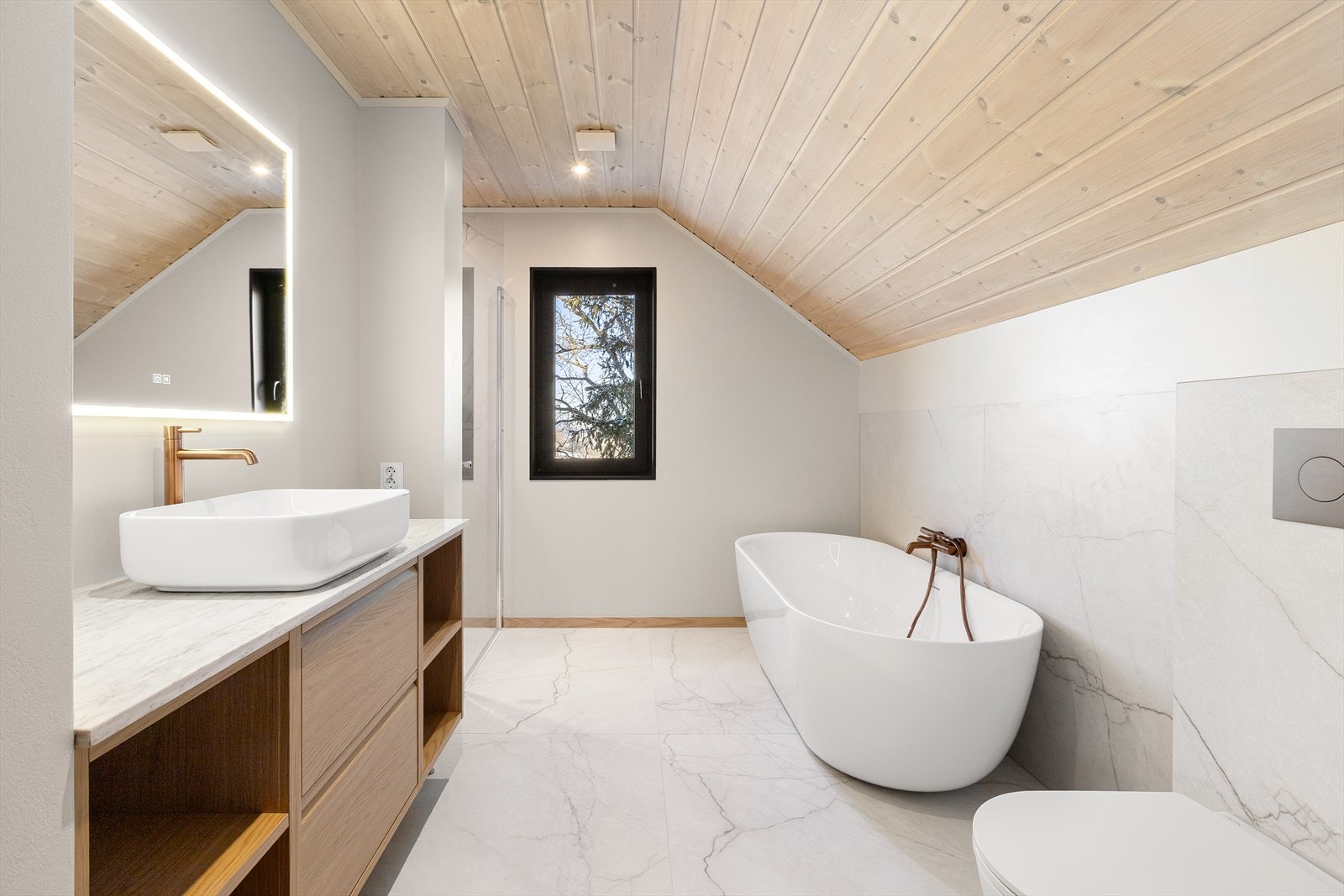 Romslig baderom i 2. etasje med god oppbevaringsplass i servantinnredning. Badet har vegghengt toalett med innebygget sisterne, moderne badekar, speil med belysning og dusjnisje. Galleribilde