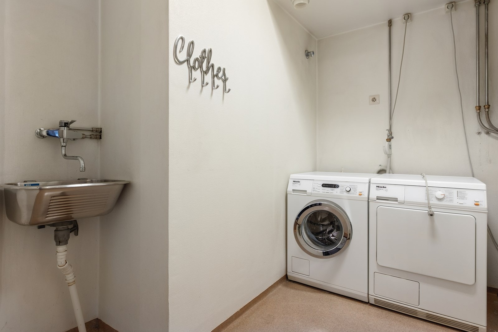 Separat vaskerom med vinylbelegg på gulvet, utslagsvask og opplegg til vaskemaskin og tørketrommel. Galleribilde