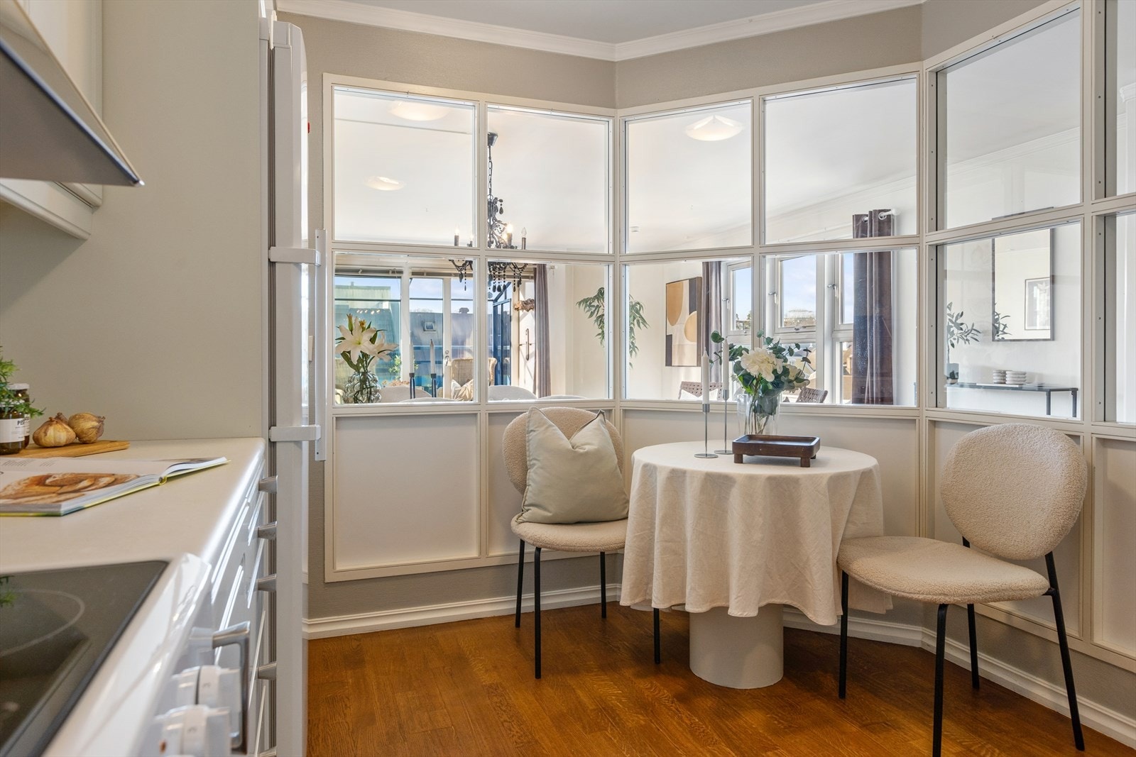 Glassvindu mot stuen bidrar til rikelig lys og skaper en harmonisk sammenheng mellom rommene. Hyggelig spiseplass på kjøkkenet. Galleribilde