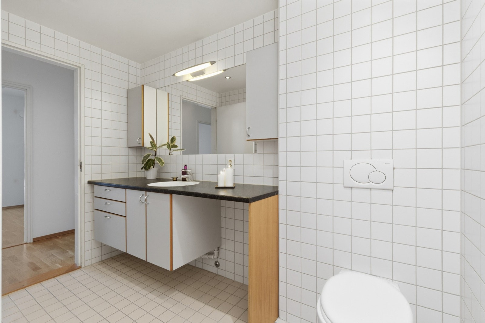 Badet er innredet med, nedfelt servant, veggmontert toalett, dusjhjørne og opplegg for vaskemaskin. Galleribilde