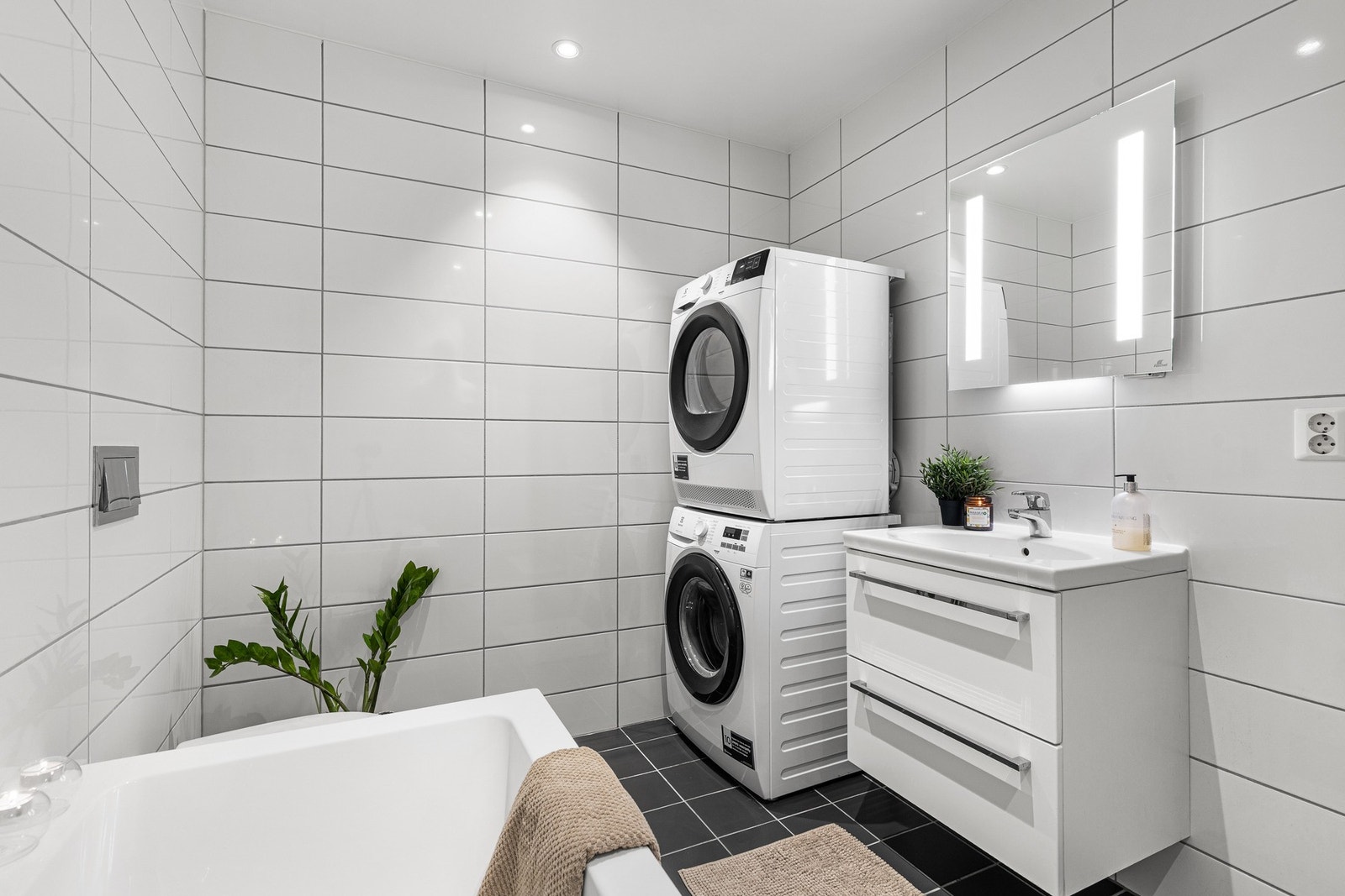 Her er det hvit baderomsinnredning med skuffer og heldekkende servant, samt speil med lys over. Det er også opplegg for vaskemaskin og tørketrommel. Galleribilde