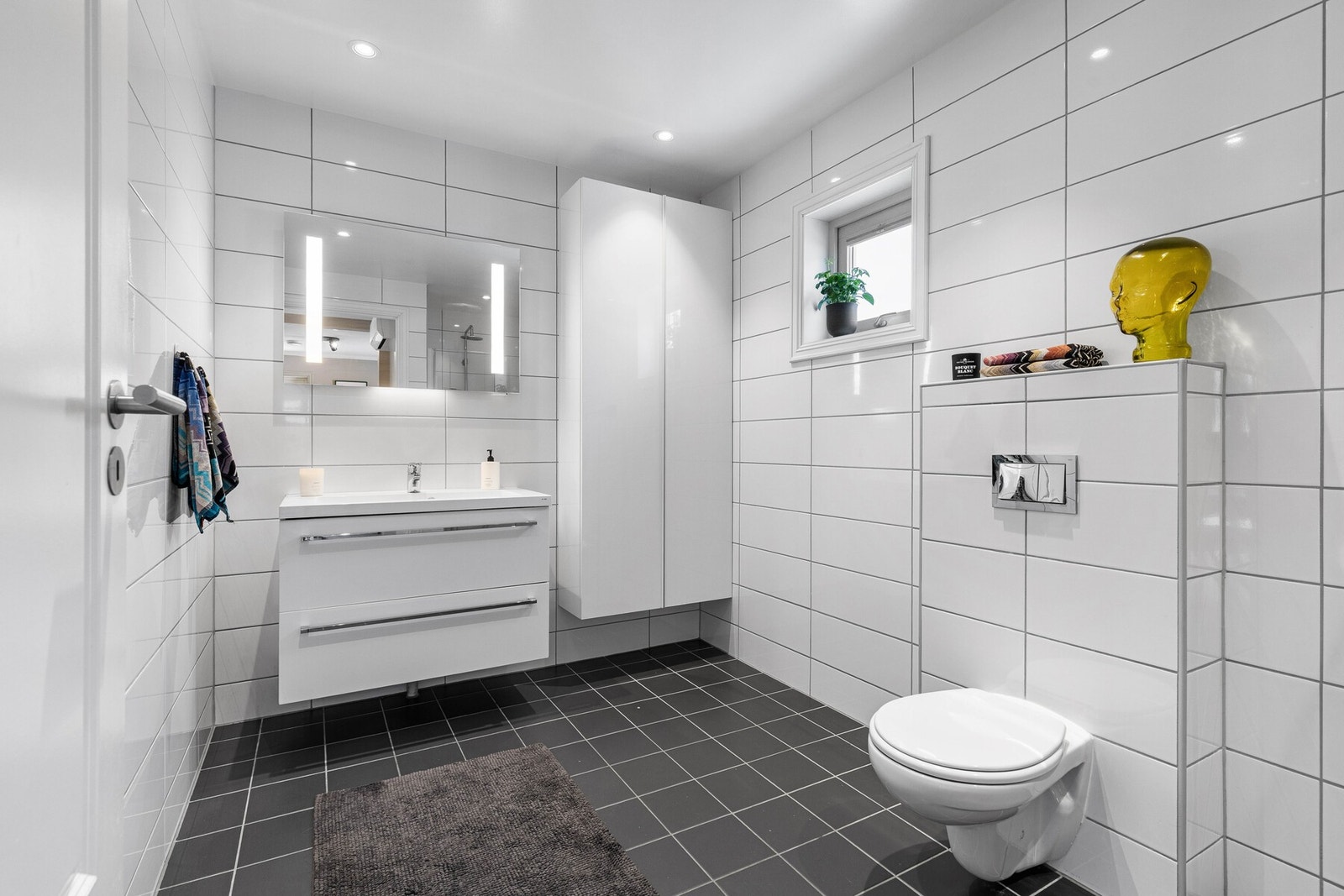 Badet i andre etasje er stilrent innredet med mørke fliser på gulvet og hvite fliser på veggene. Galleribilde