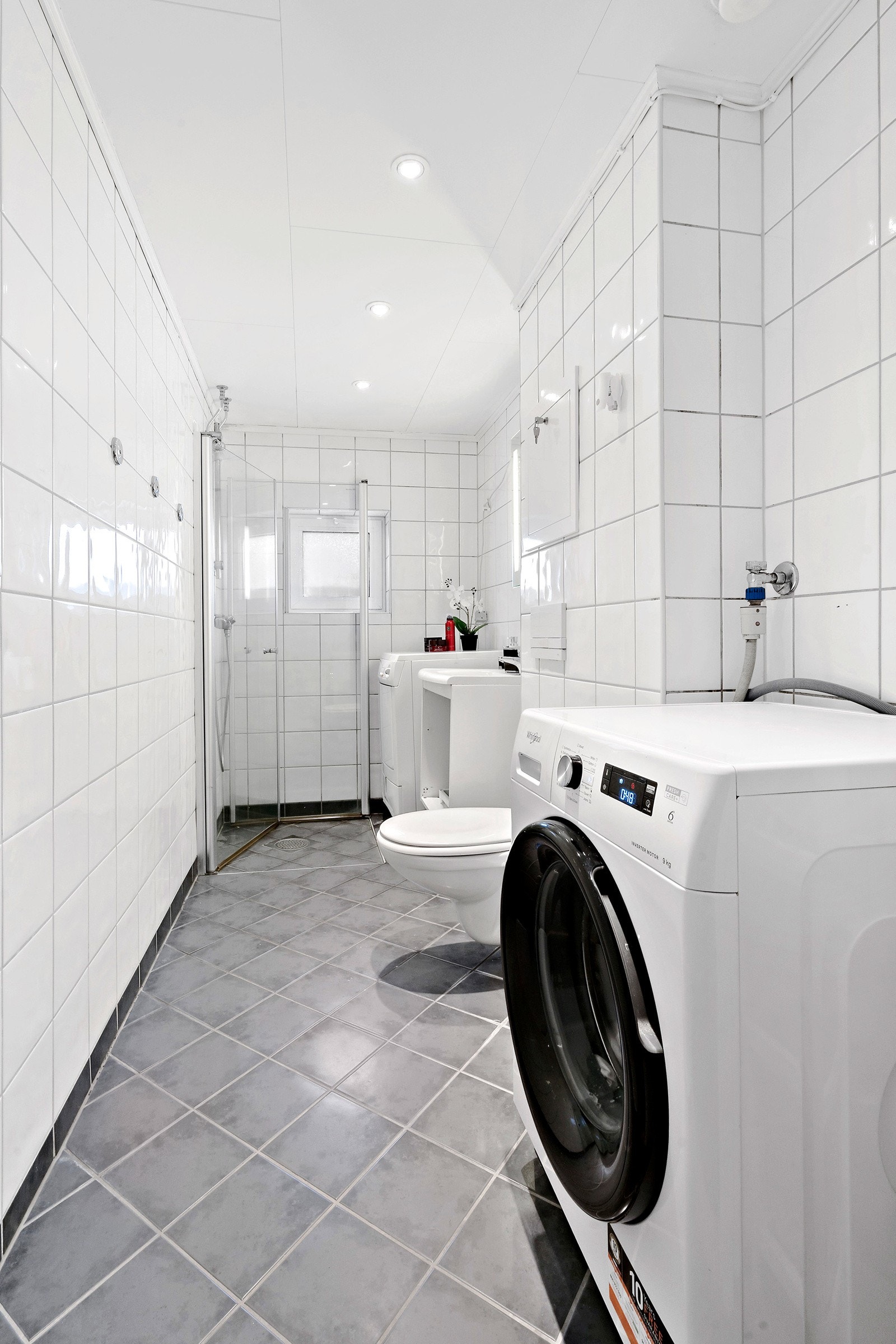 Badet har plass til vaskemaskin. FLiser på gulv og vegger. Galleribilde