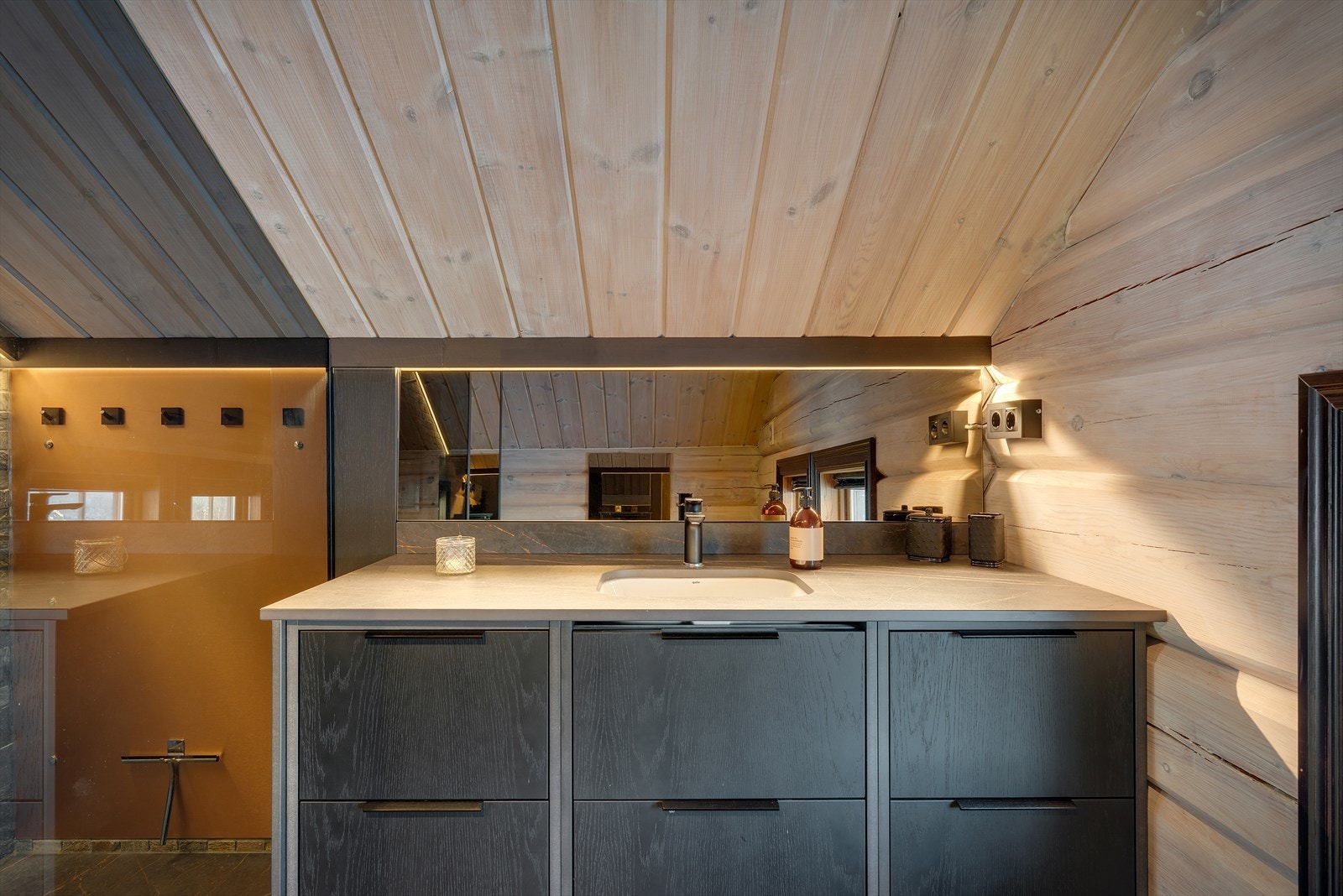 Badet er innredet med finérte fronter, silestone benkeplate og underlimt porselensservant, speil, belysning, vegghengt toalett og dusjnisje. Galleribilde