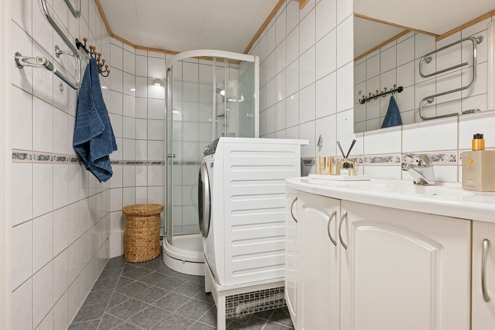 Lyst og pent bad utstyrt med dusjkabinett, vegghengt toalett og opplegg for vaskemaskin. Galleribilde