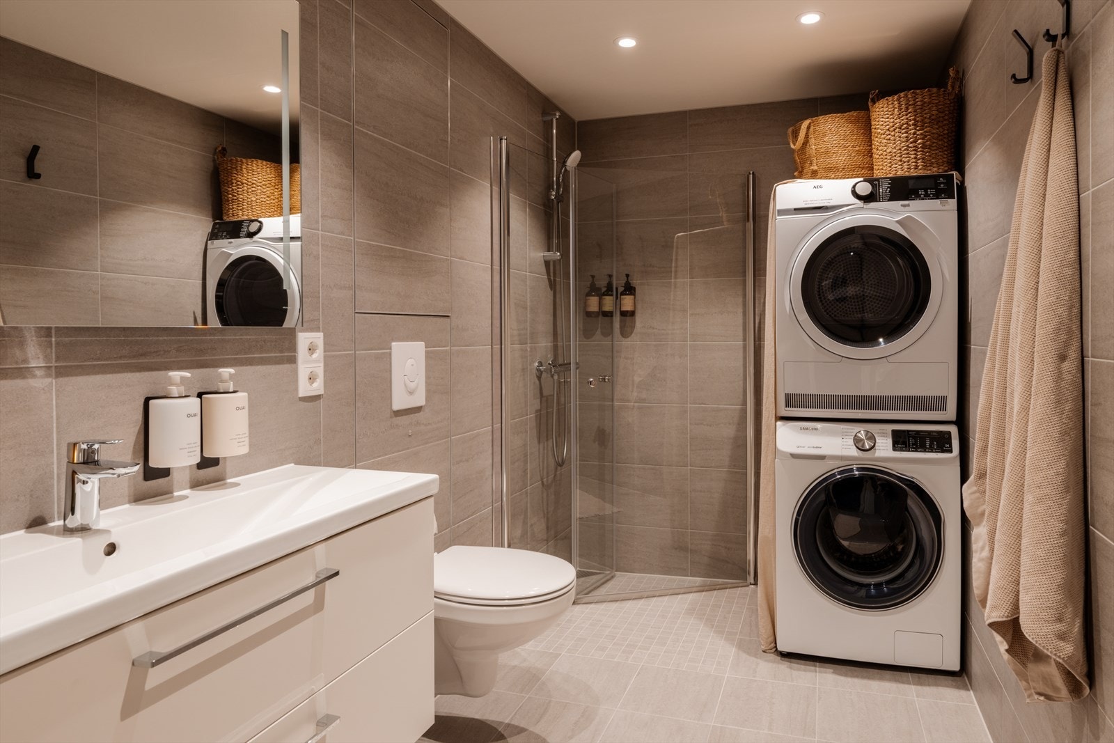 Leilighetens baderom er flislagt i en lun fargepalett og det er selvsagt varme i gulvet. Galleribilde