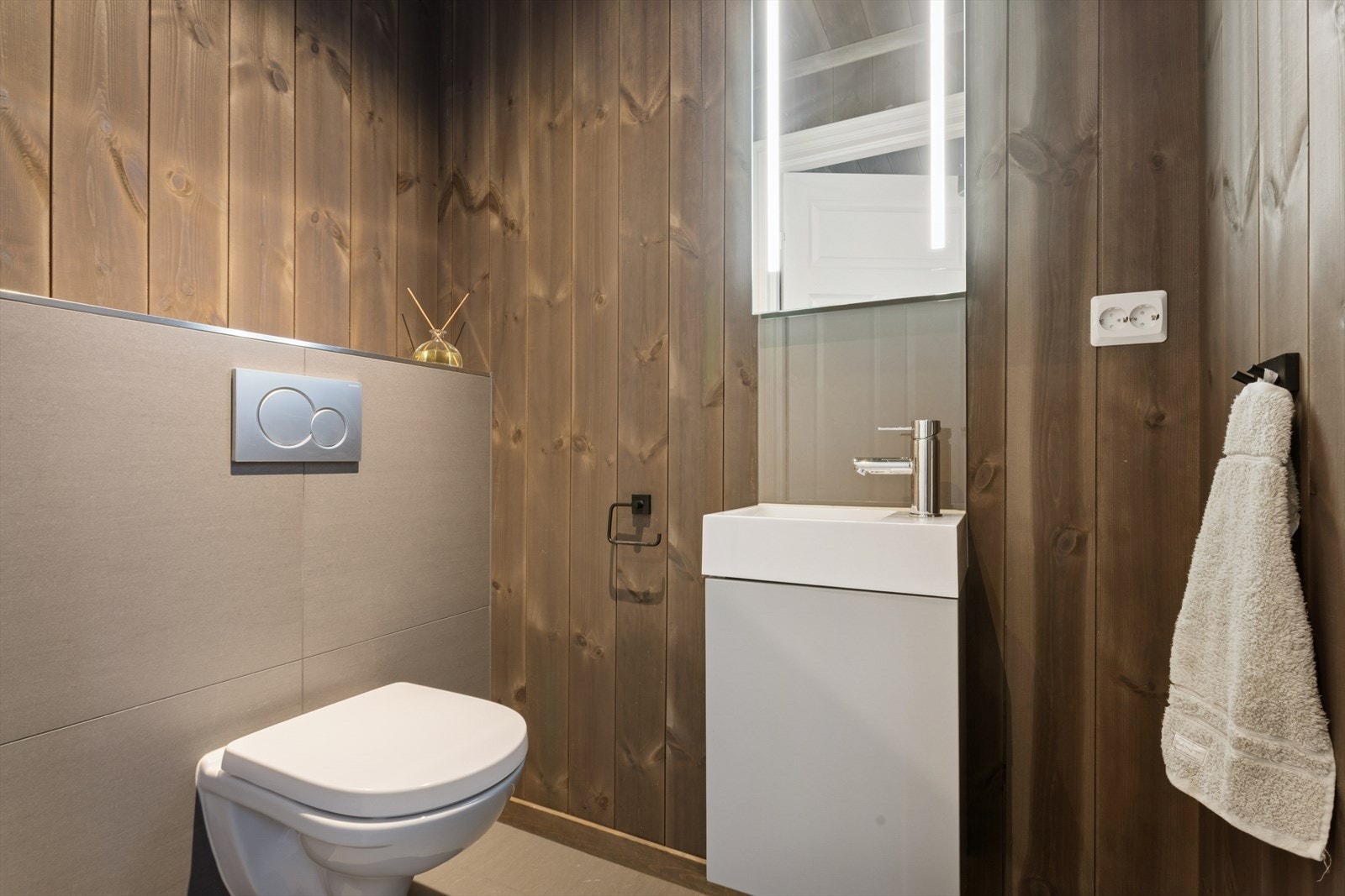 I tilknytning til entreen finner man også et praktisk toalettrom som er innredet med flislagt gulv og panel på vegg. Rommet er ellers utstyrt med vegghengt toalett og baderomsinnredning med nedfelt servant. Galleribilde