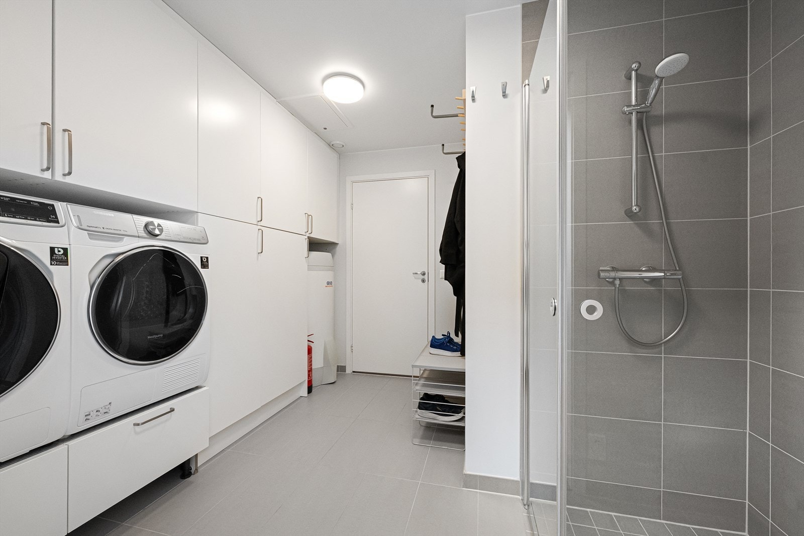 Romslig vaskerom med integrert dusj og praktiske oppbevaringsløsninger Galleribilde
