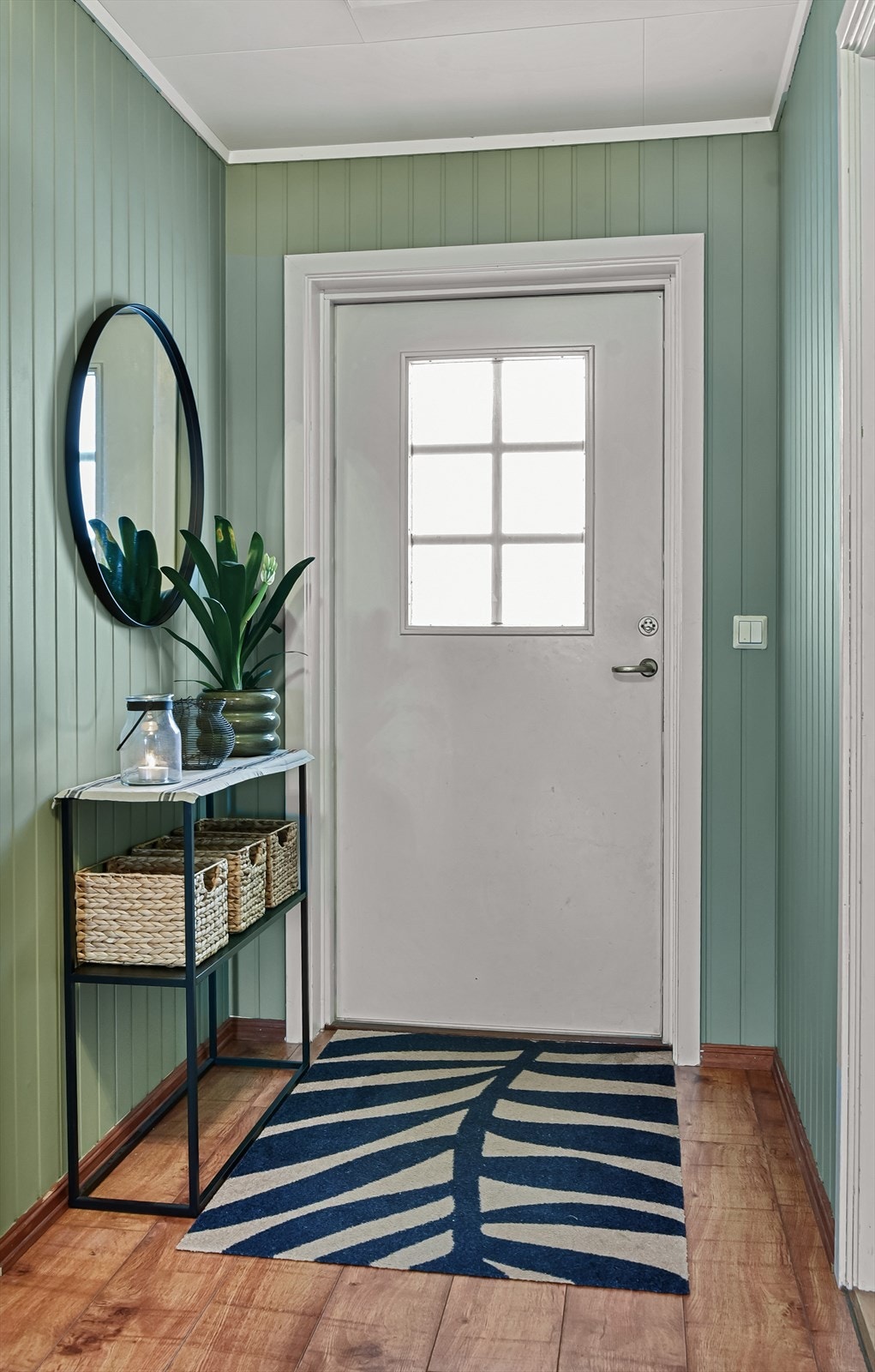 Velkommen inn i en entré med panel på veggene og laminat på gulvet. Galleribilde