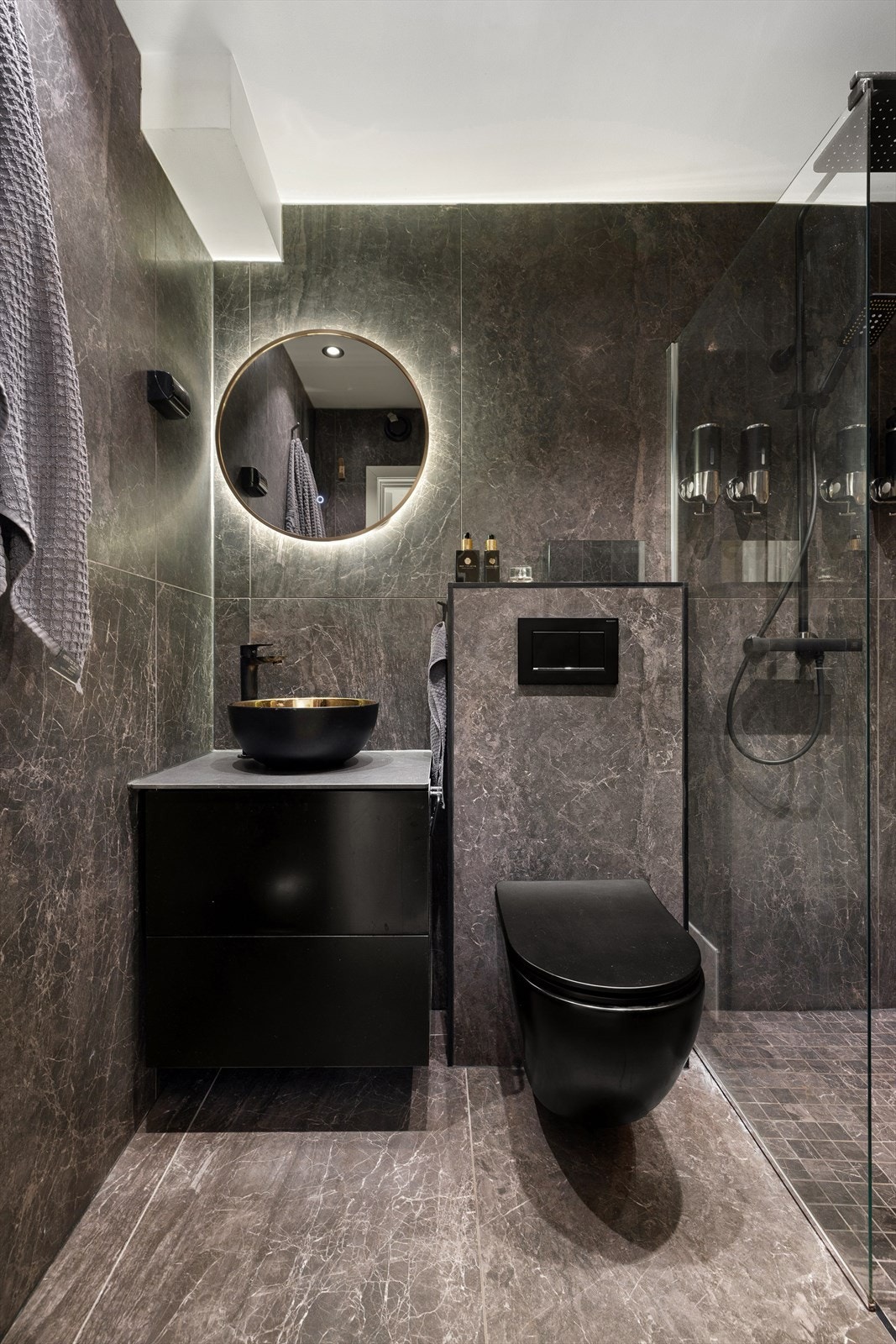 Stilrent bad med moderne uttrykk, flislagte overflater, vegghengt toalett og dusj med glassvegger. Galleribilde