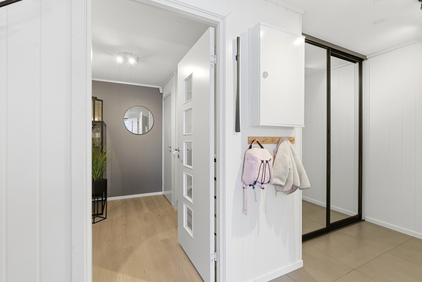 En lys og moderne entré med flislagt gulv med varme som både gir et elegant uttrykk og en svært praktisk løsning i hverdagen. Galleribilde