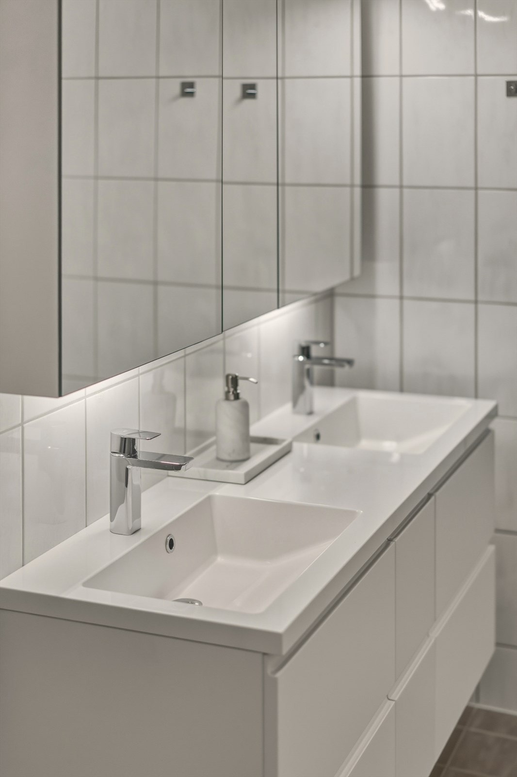 Baderomsinnredning med dobbelservant og rom for oppbevaring i skuffer og speil med belysning. Galleribilde