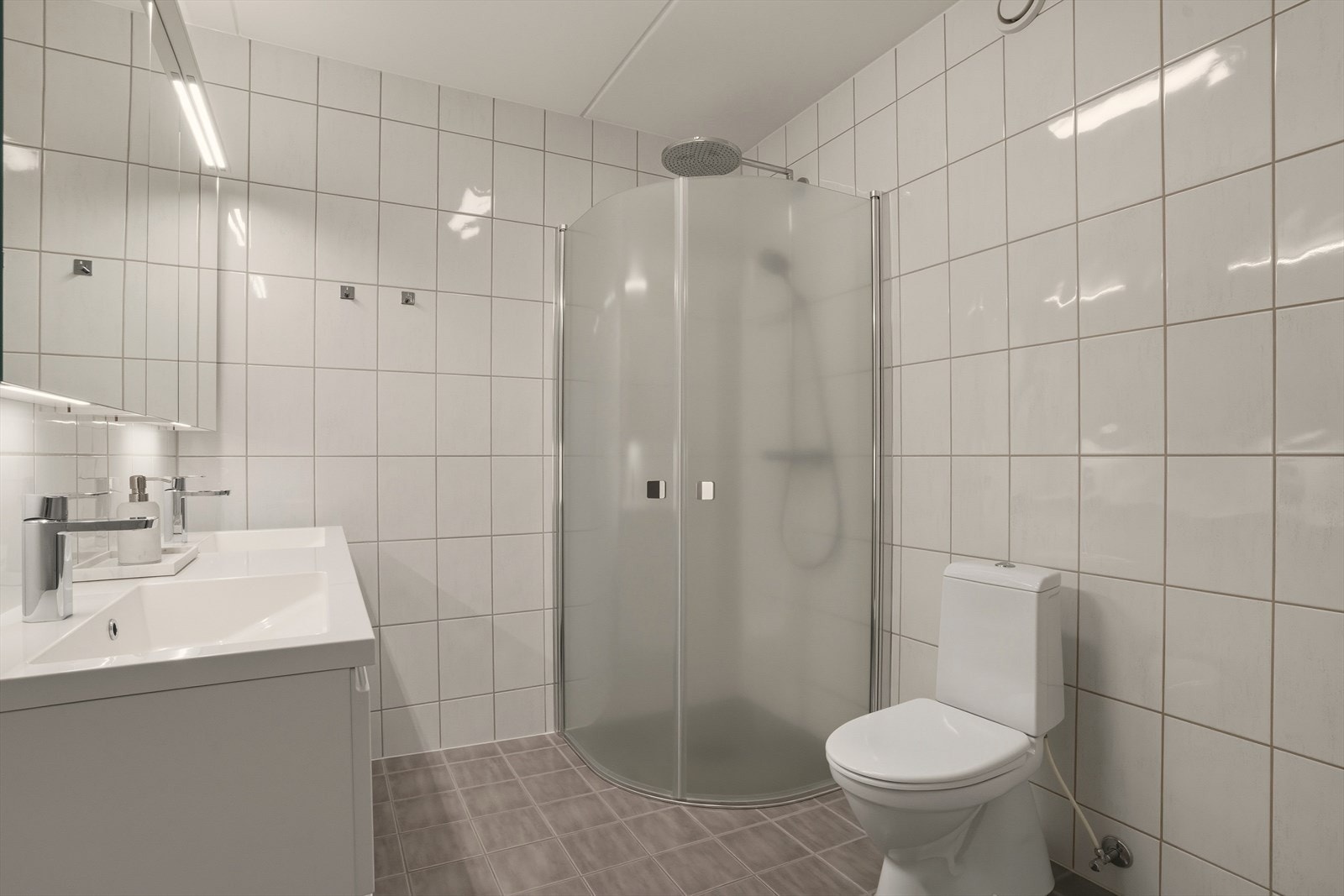 Badet er videre utstyrt med toalett og dusjhjørne med regndusjarmatur. Galleribilde