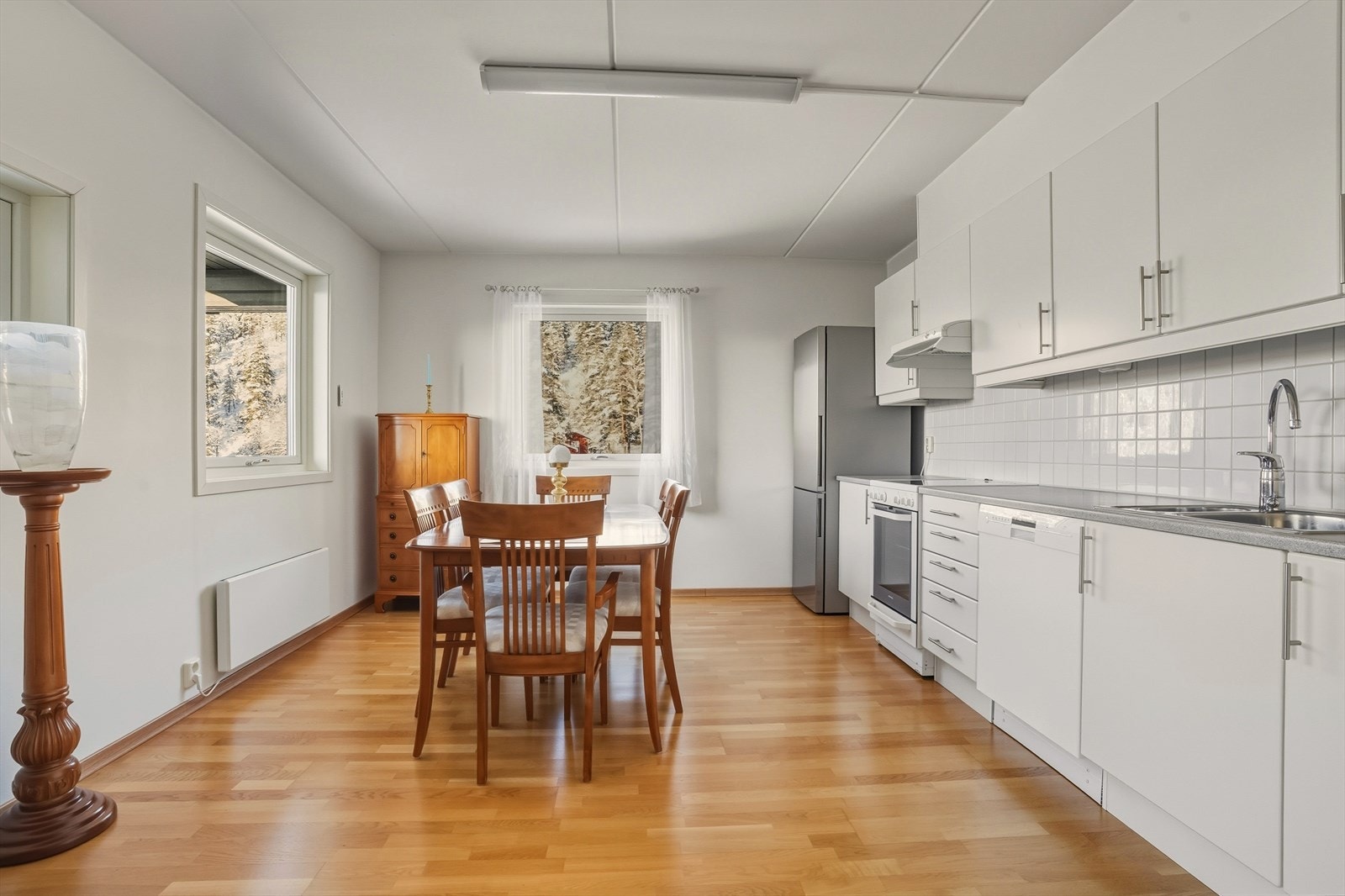 Klassisk kjøkkeninnredning med hvite, slette fronter og benkeplate av laminat. Veggen bak kokesonen er flissatt. Galleribilde