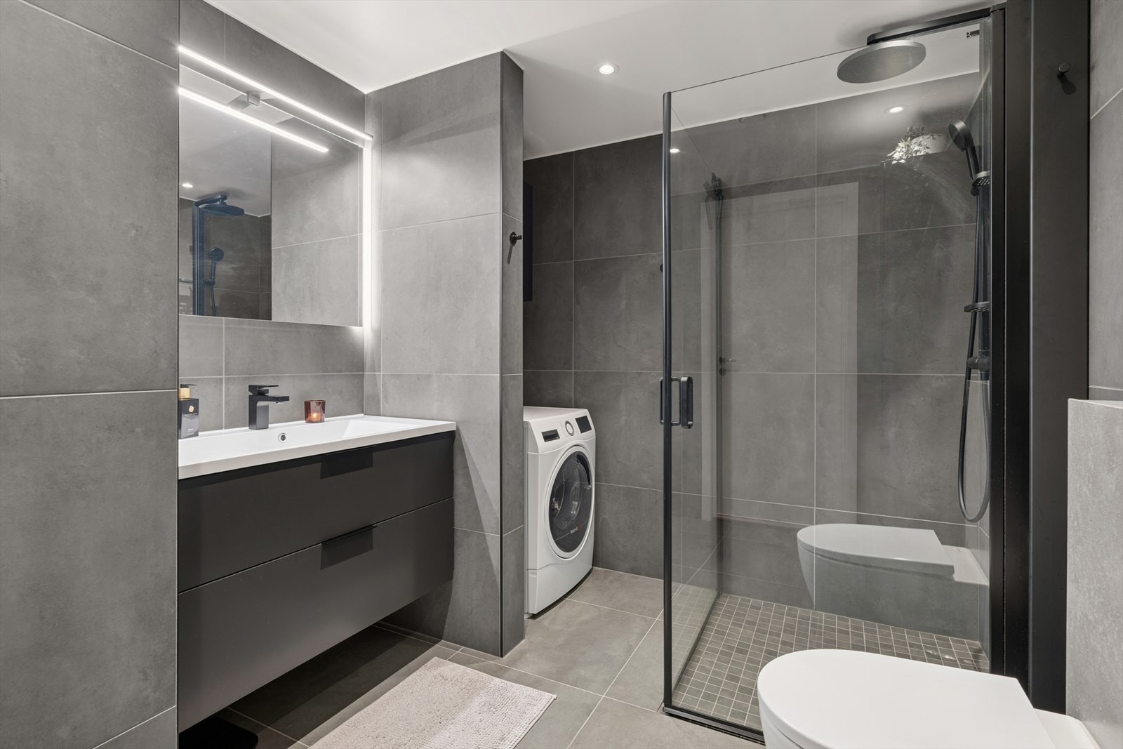 Baderommet fremstår som både innbydende og praktisk, med flislagt gulv i betong og behagelige varmekabler som gir ekstra komfort. Galleribilde