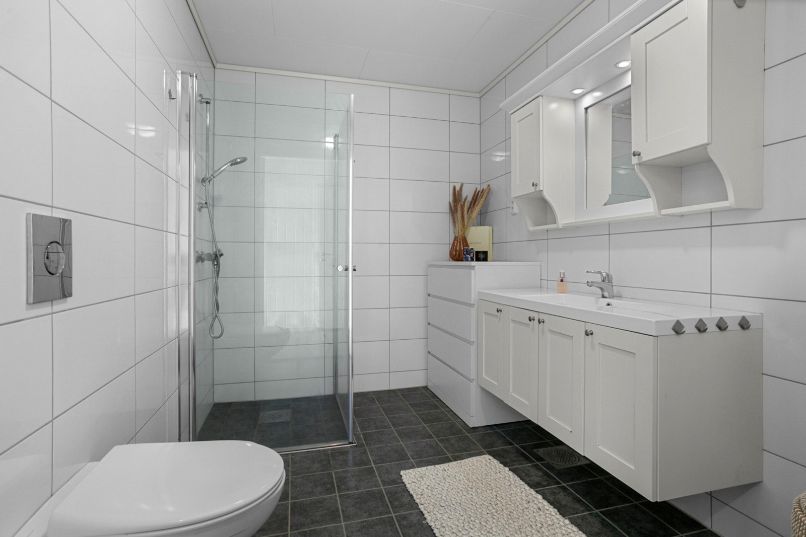 Badet er utstyrt med baderomsinnredning, toalett og dusjhjørne Galleribilde