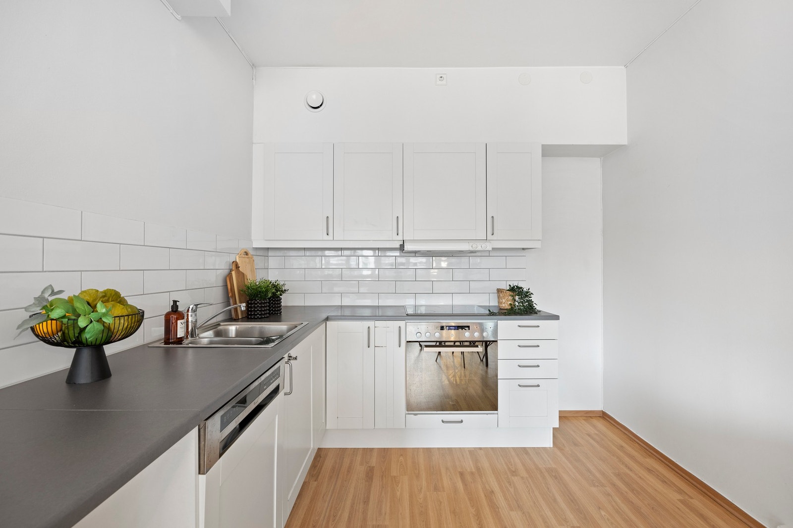 Sigdal kjøkkeninnredning med hvite fronter, laminert benkeplate, lys under overskap, ventilator med platetopp og stålkum med blandebatteri. Plass til kjøleskap og opplegg til vaskemaskin. Galleribilde