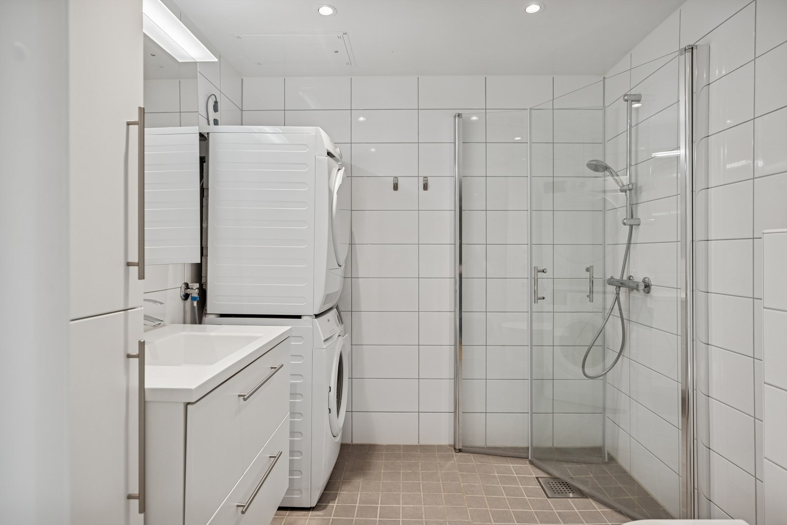 Badet er utstyrt med dusjhjørne, veggmontert toalett og opplegg for vaskemaskin. Galleribilde