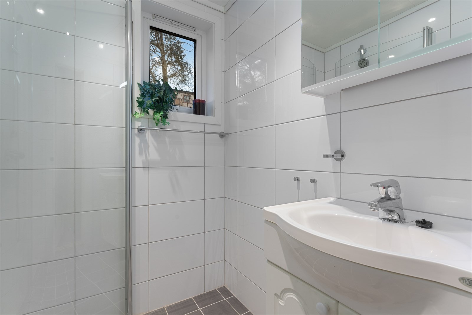 - Badet er innredet med benkeskap med servant, speilskap med belysning og dusjdører i glass - Galleribilde