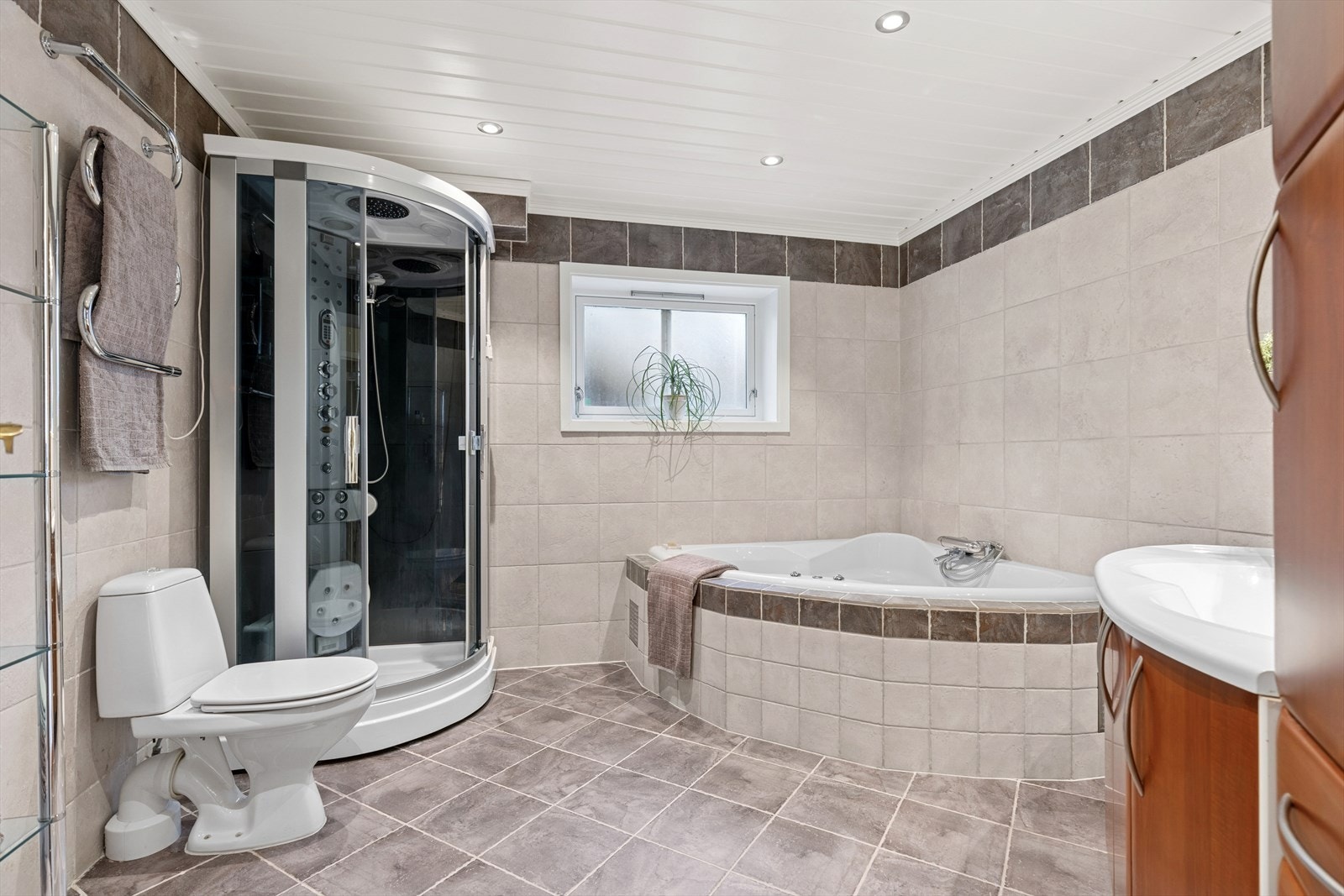 Stort baderom i underetasjen som er helfliset og innredet med nedfelt servant, toalett, håndkletørker,
dusjkabinett og badekar. Galleribilde