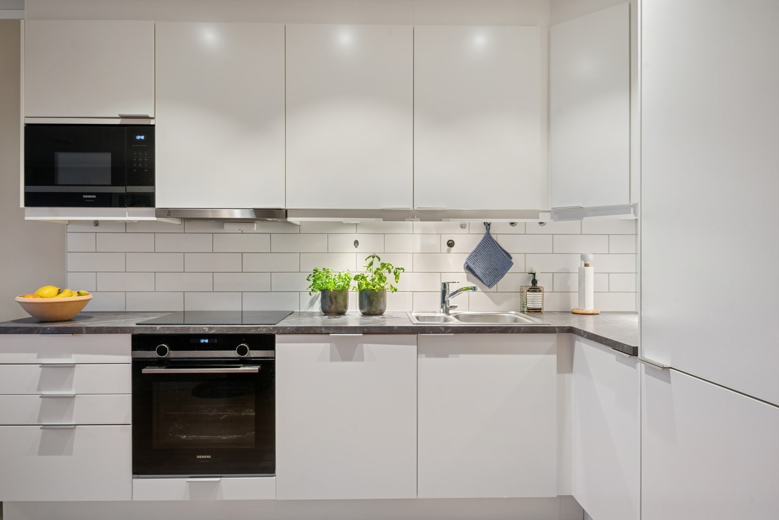 Kjøkkenet er videre innredet med hvite, glatte fronter, laminat benkeplate, oppvaskkum i stål med ett-greps blandebatteri og fliser over kjøkkenbenk Galleribilde