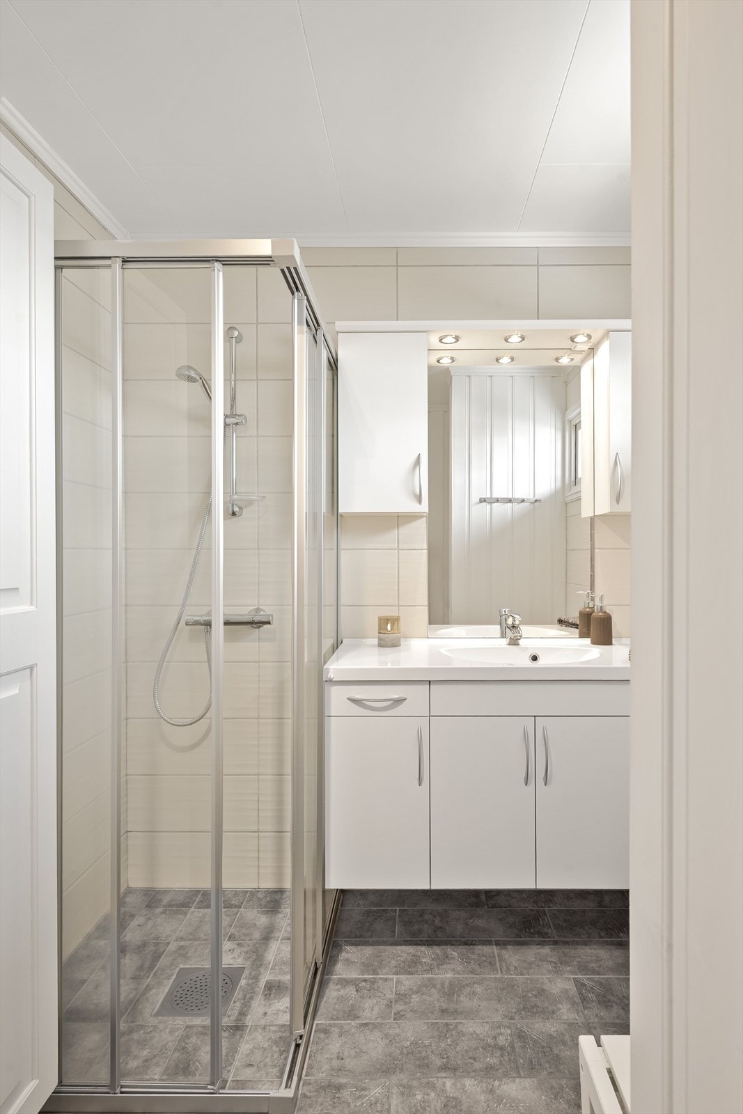 Baderommet er innredet med servant på innredning, dusjhjørne med glassdører og toalett. Galleribilde