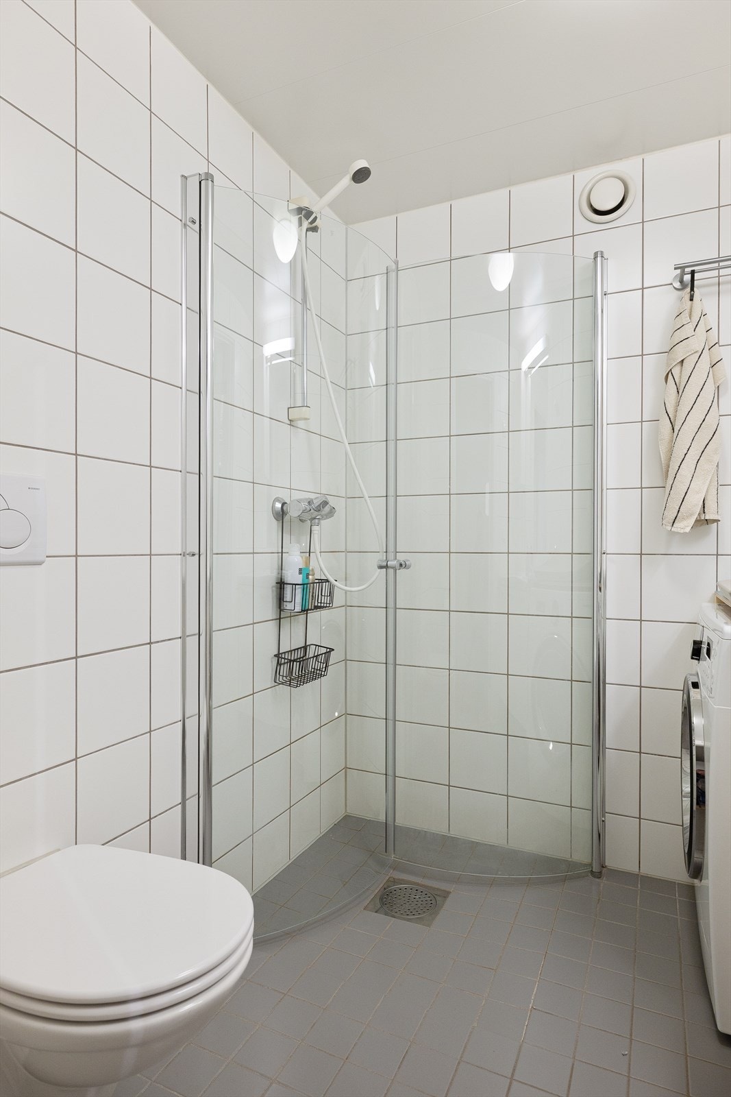 Badet er videre innredet med veggmontert wc, servantskap med ettgreps blandebatteri, speil på vegg, belysning samt opplegg for vaskemaskin og mekanisk avtrekk. Galleribilde