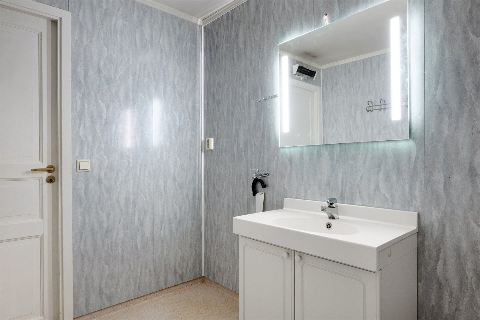 Rommet er innredet med lys skapinnredning, speil med integrert belysning, dusjhjørne og gulvmontert wc. Galleribilde