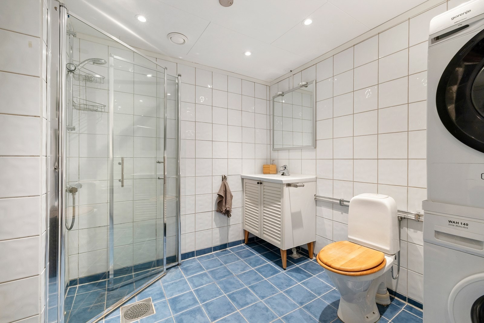 Dusjen er plassert på gulvet i hjørnet og har innfellbare dører for plassbesparelse og enkel tilkomst. Dusjbatteri er tilkoblet en veggmontert hånddusj for fleksibel bruk. Toalettet er frittstående. Galleribilde