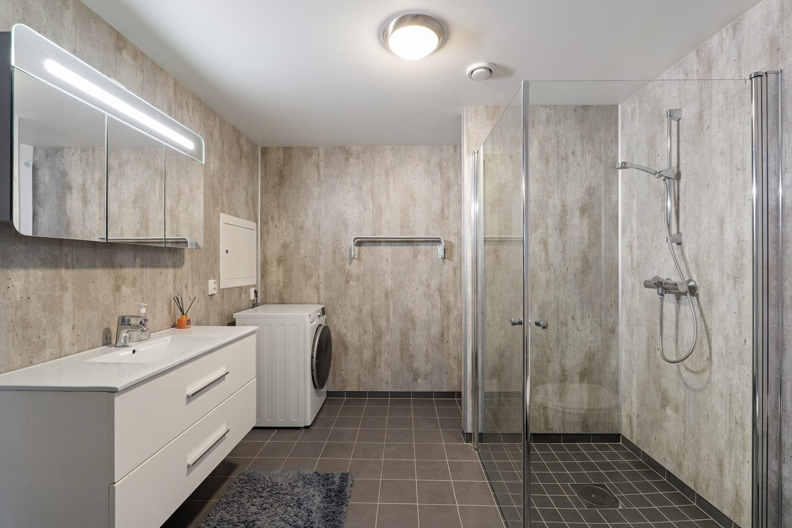 Stilrent bad med vegghengt servant, dusjhjørne og opplegg for vaskemaskin Galleribilde