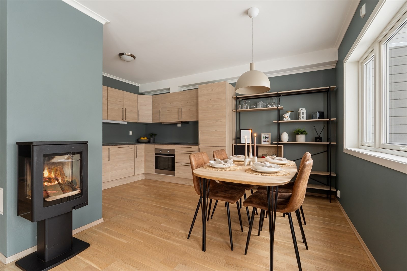 Kjøkkenet har en naturlig spiseplass med vedovn som gir rommet et lunt preg Galleribilde