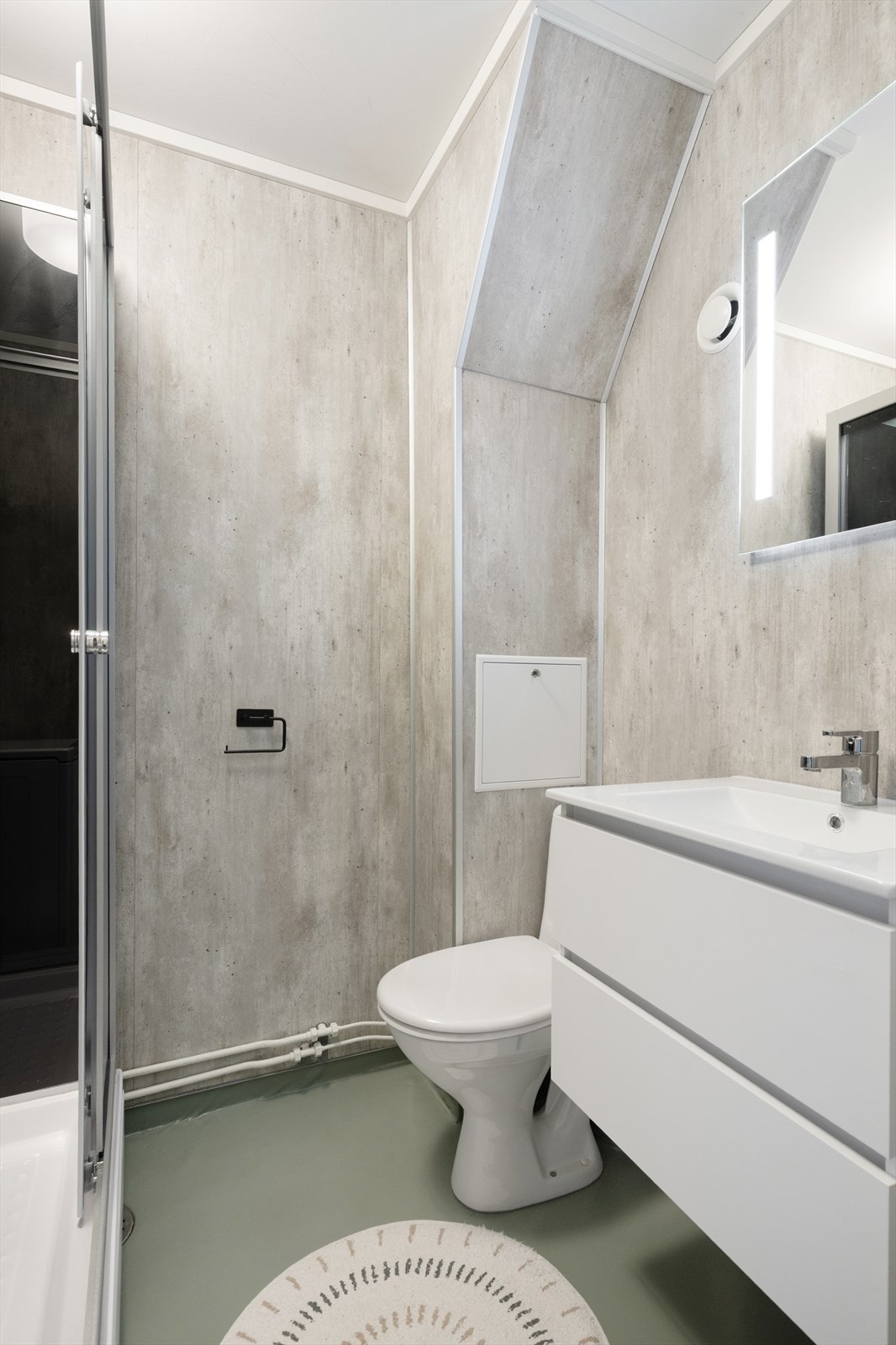 Baderommet har innredning med praktiske underskuffer med hvite, glatte fronter og heldekkende servantplate over. Speil over vask. Galleribilde